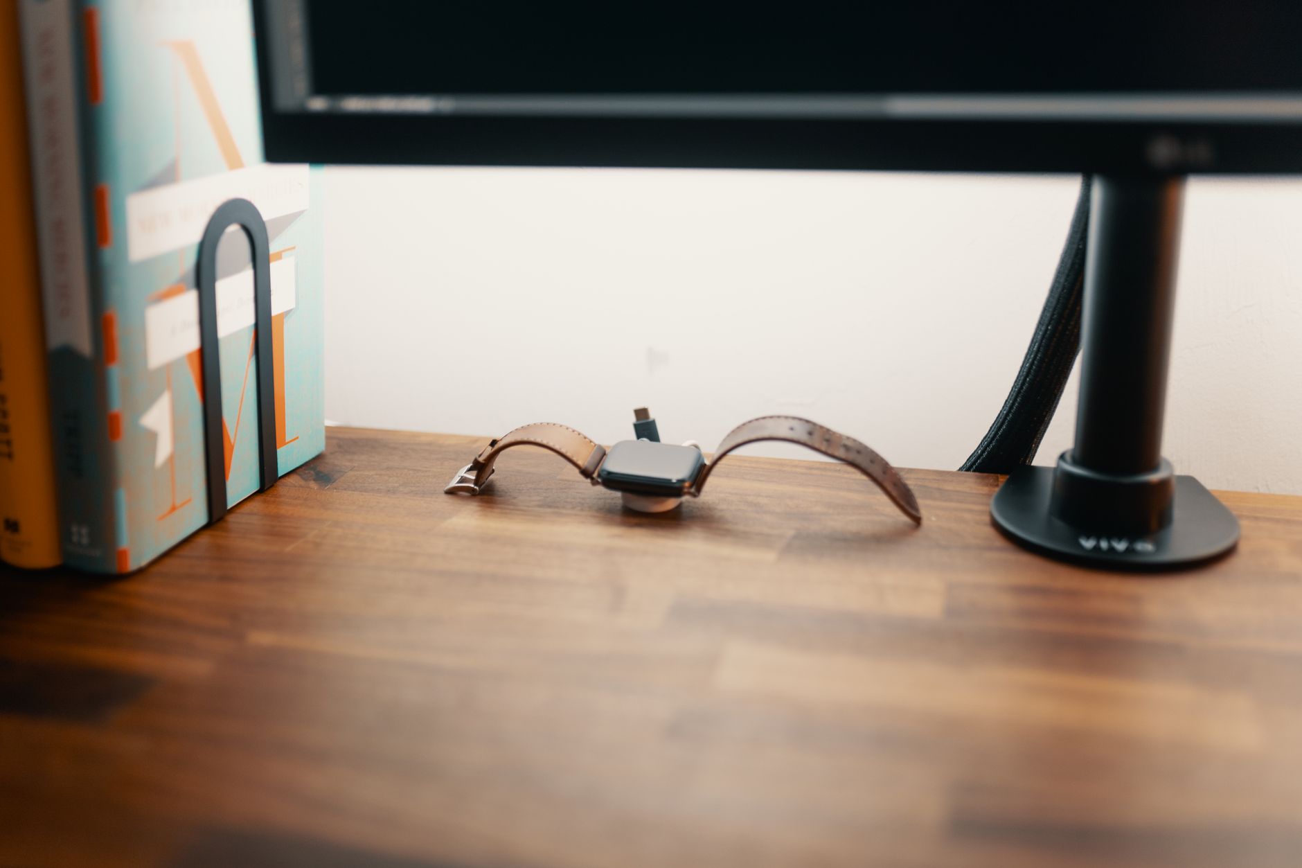 A minimalist desk featuring a smartwatch charger and books, ideal for a productive workspace.