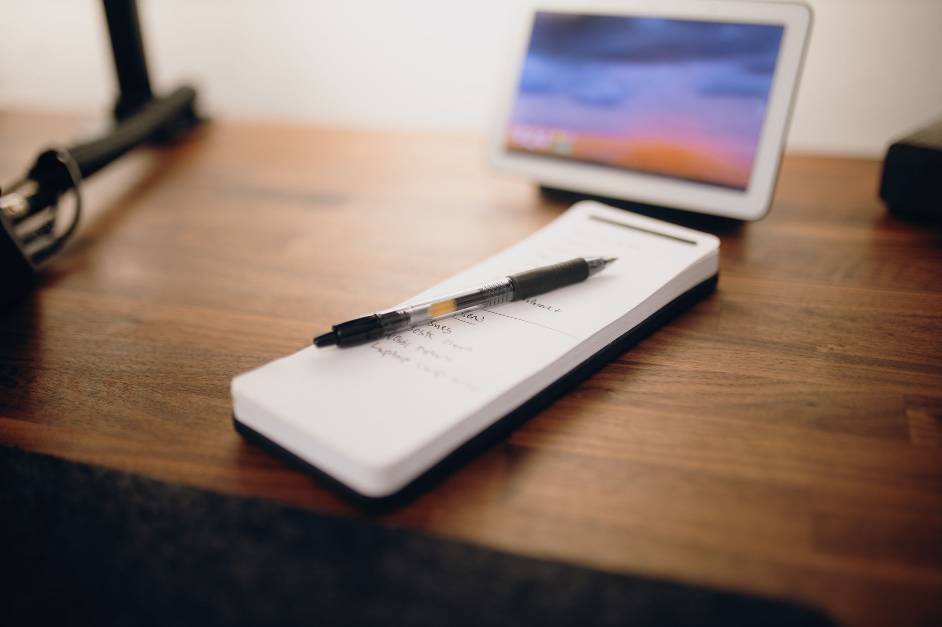 A contemporary work desk featuring a notepad, ball pen, and digital tablet.