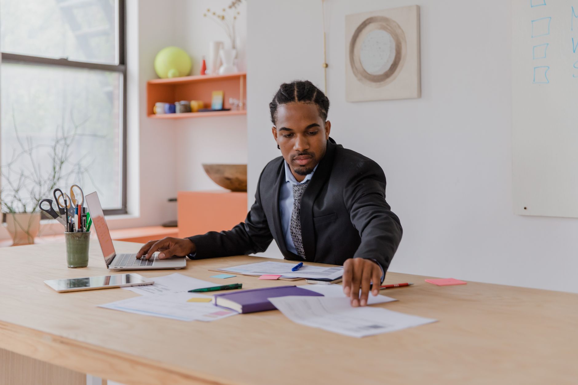 Focused businessman in office organizing documents at a modern desk.