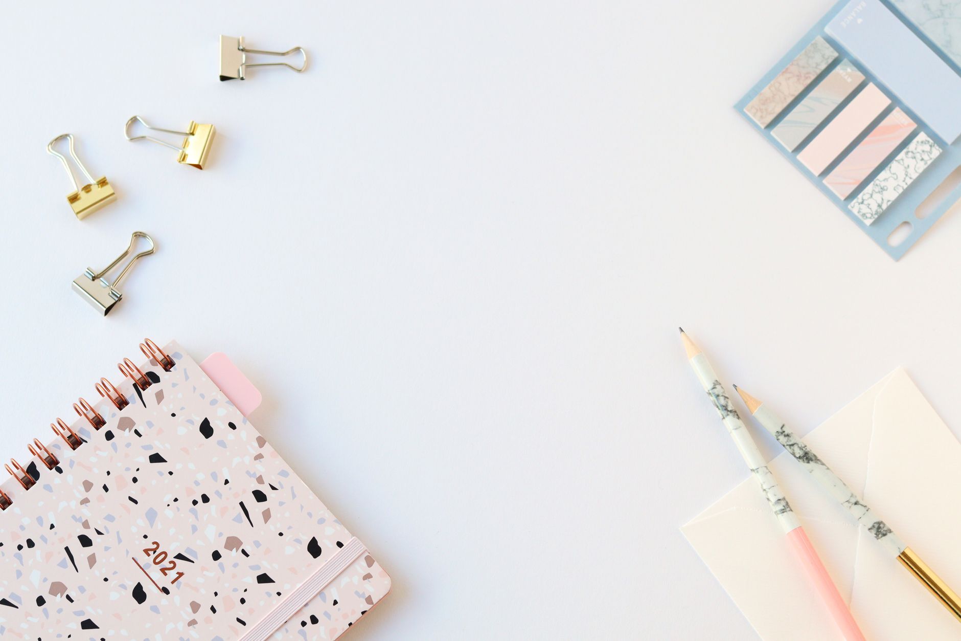 Flat lay of a stylish 2021 planner and stationery on a white desk, perfect for planning and organization.