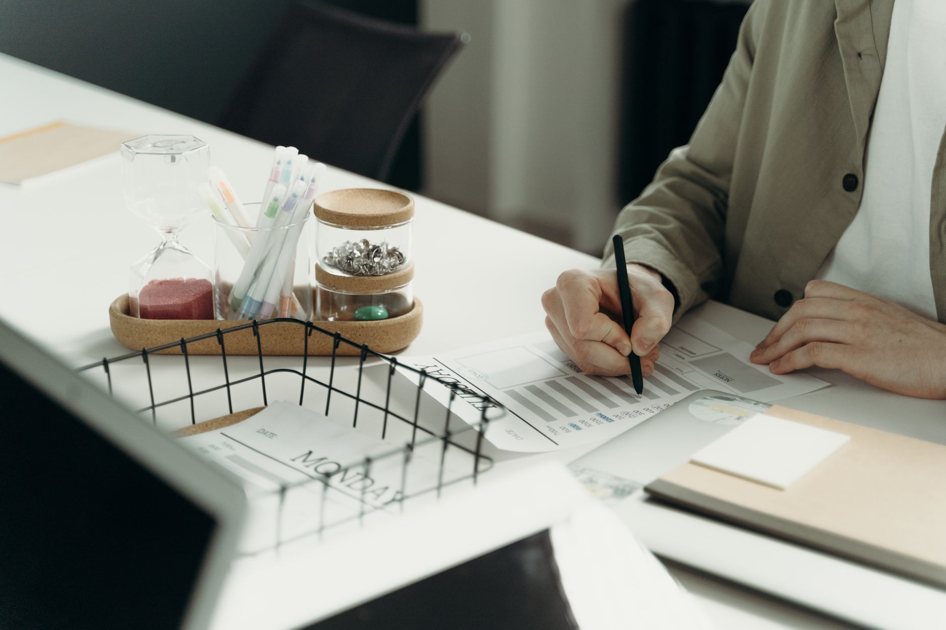 A person writing on a document at a tidy desk with office supplies.