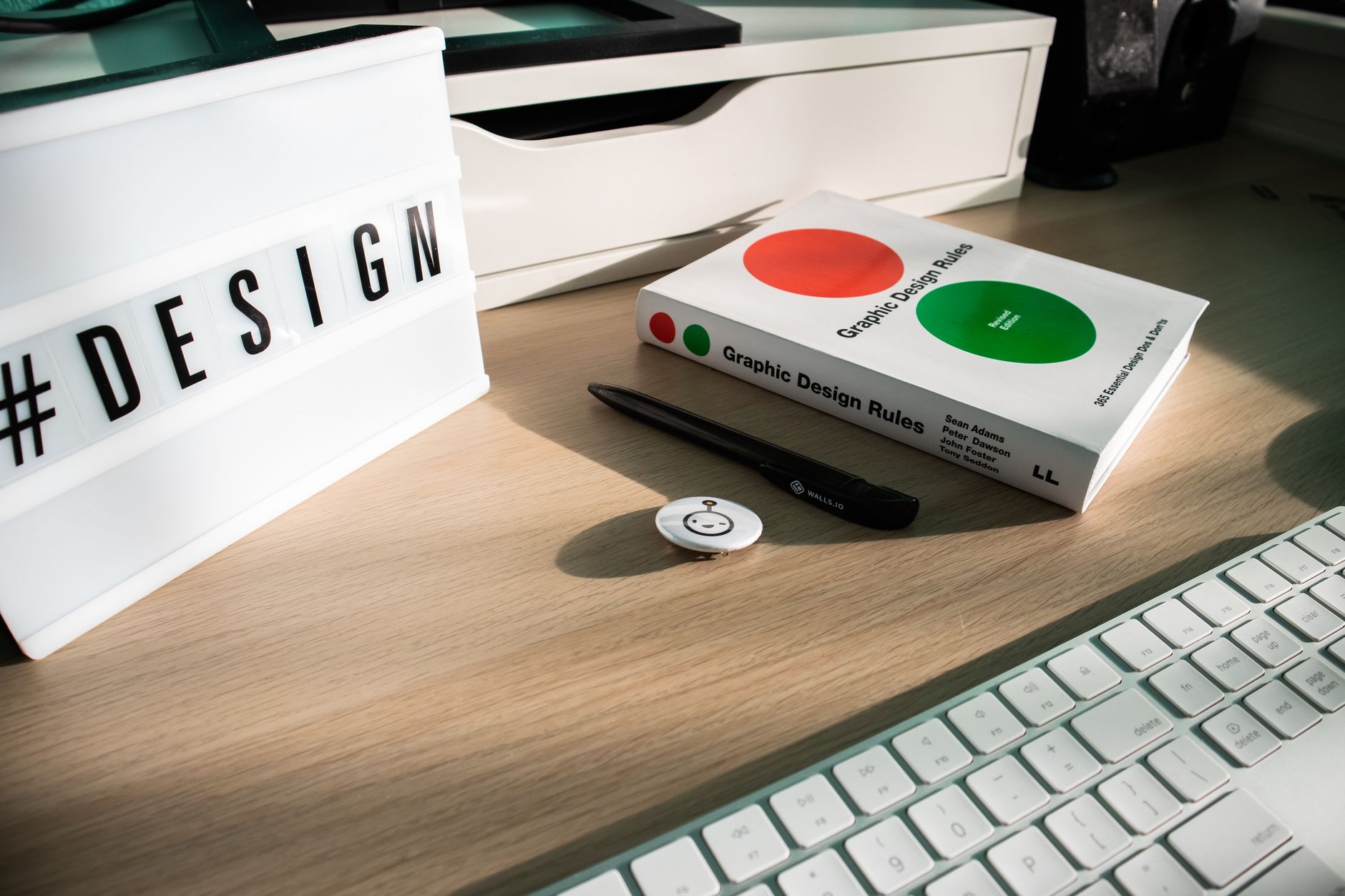 A modern desk setup featuring design elements like a book, #DESIGN sign, and accessories.