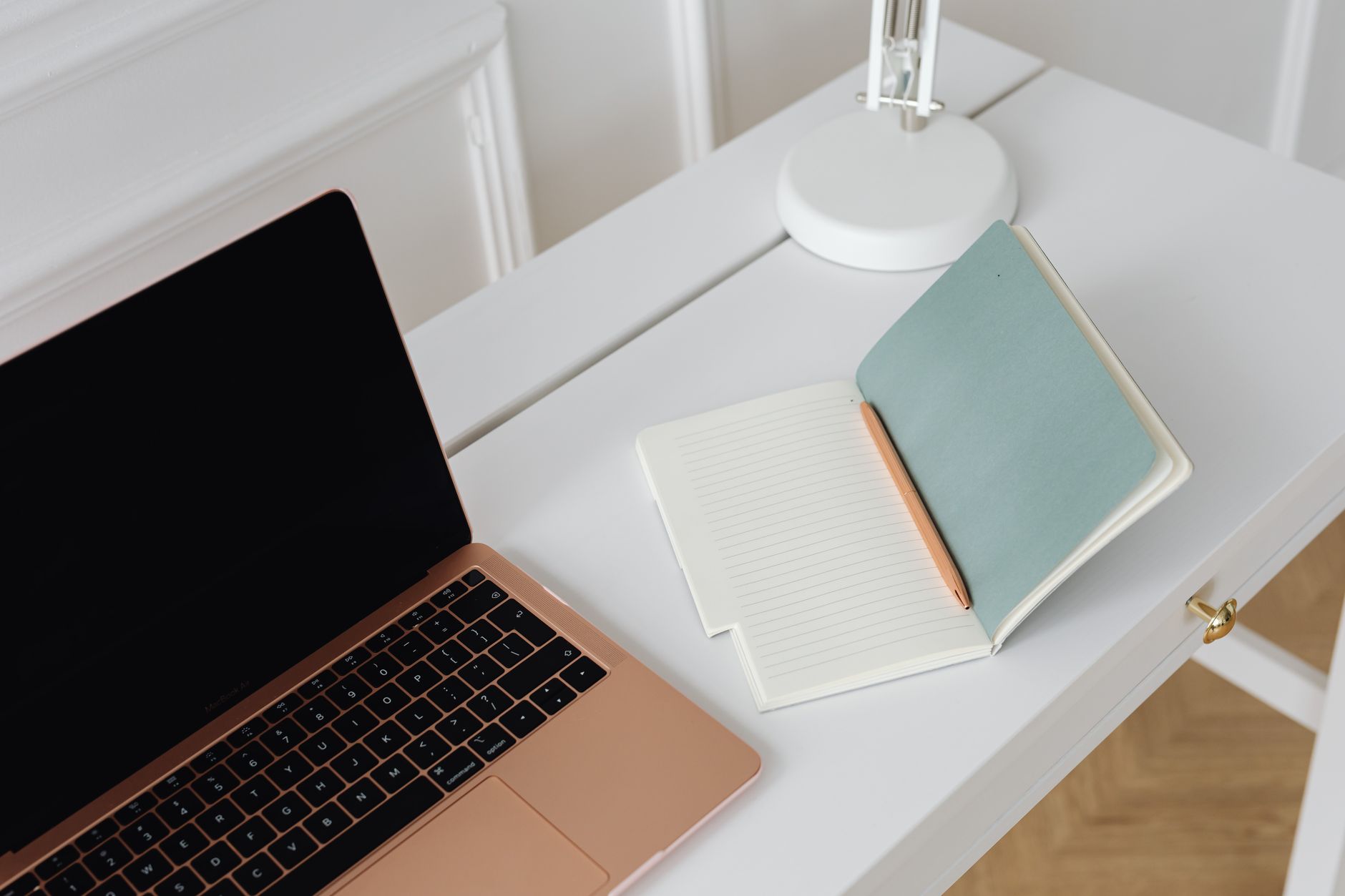 A clean and minimalist workspace featuring a laptop on white desk.