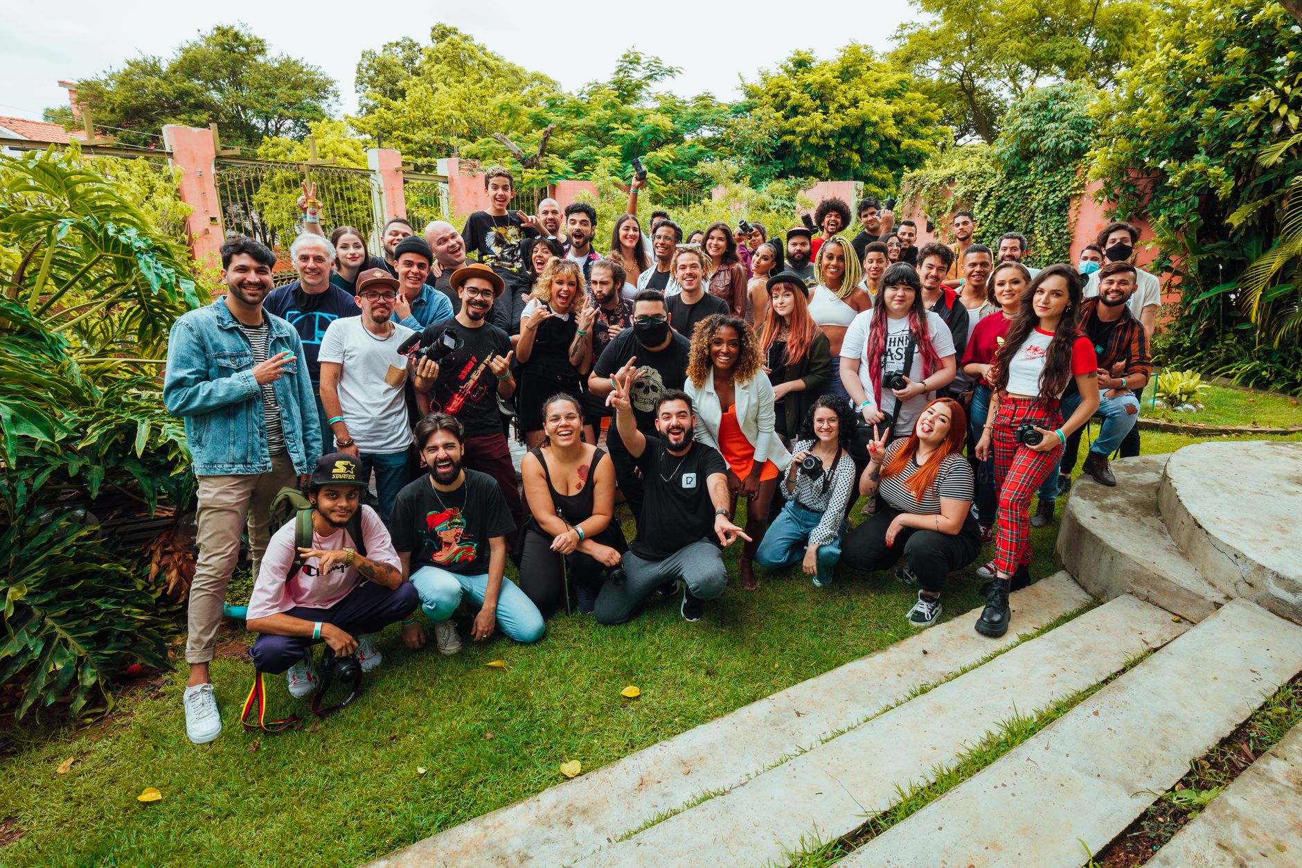 A vibrant group of people posing joyfully together outdoors in a lush garden area, displaying diversity and community spirit.
