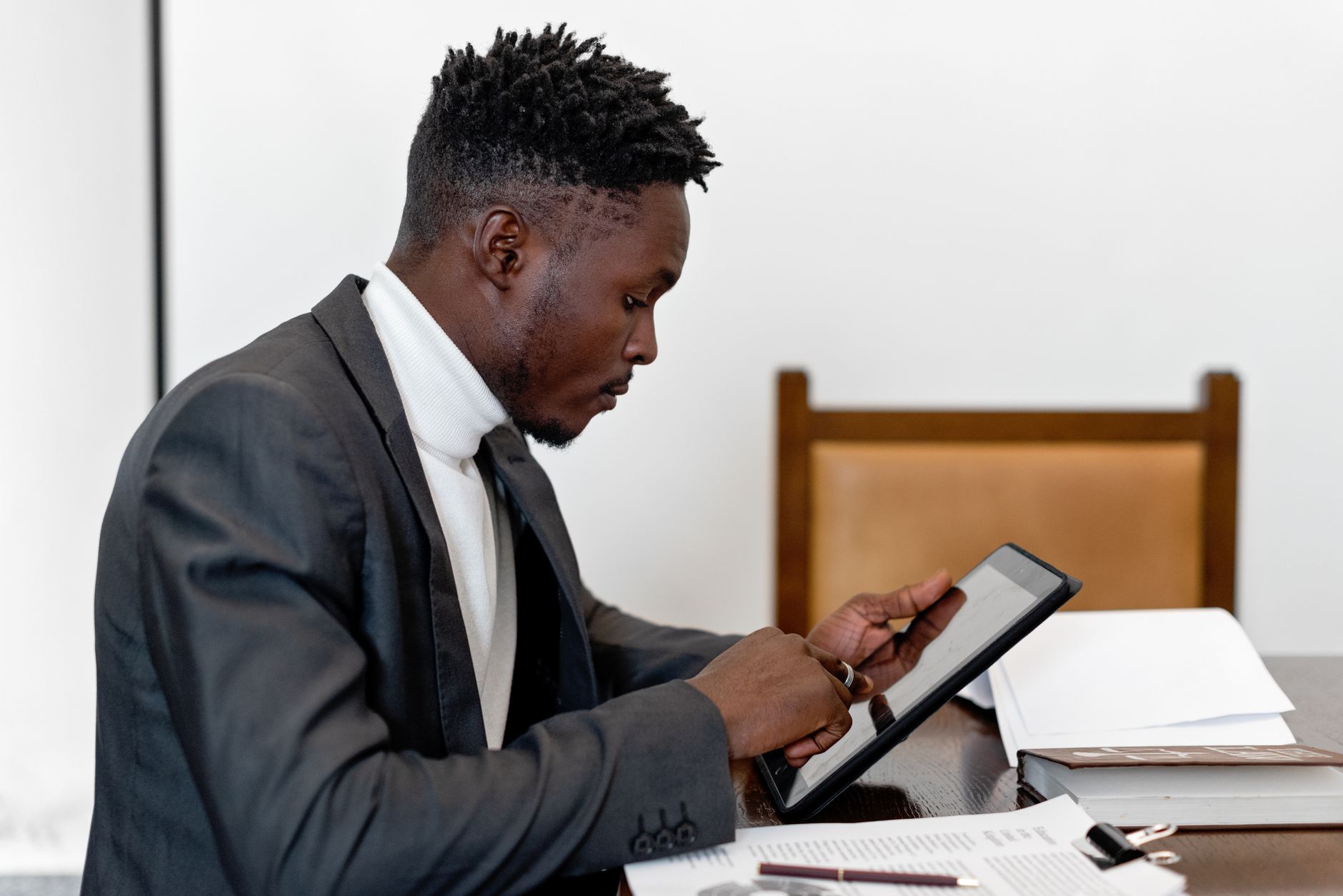 Businessman in elegant suit using tablet during office meeting, focusing on touchscreen technology.