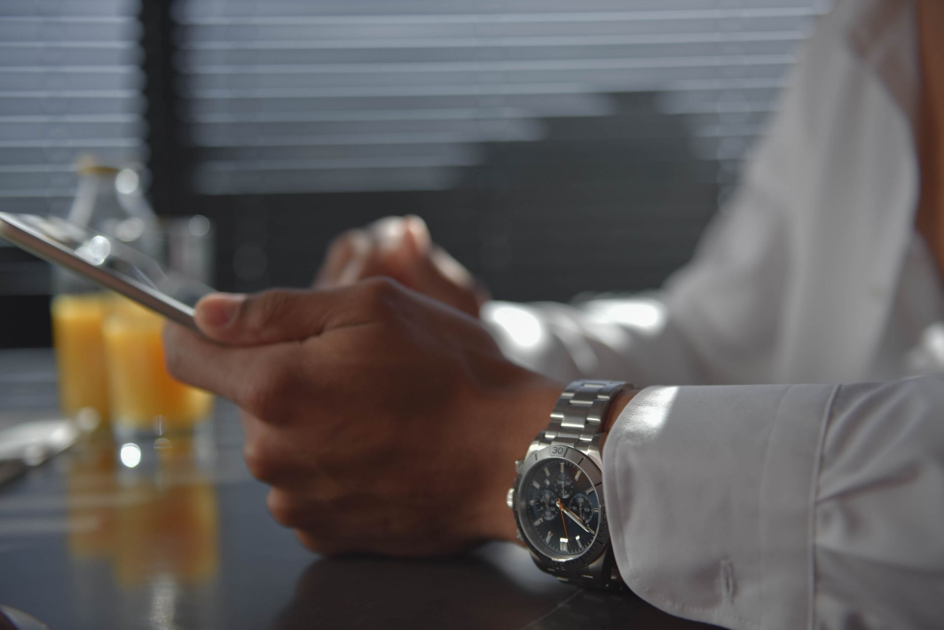 A man wearing a wristwatch holding a tablet in a softly lit room. Morning ambiance.