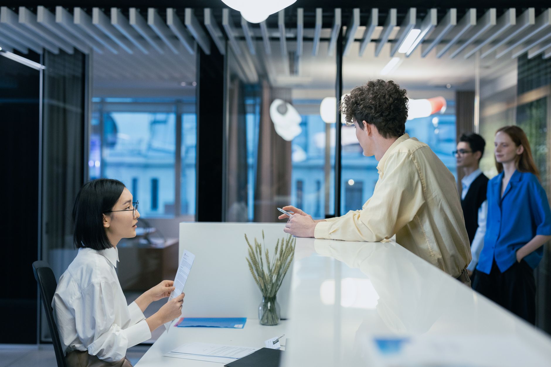 Employees interacting at a sleek office reception desk, fostering professional collaboration.