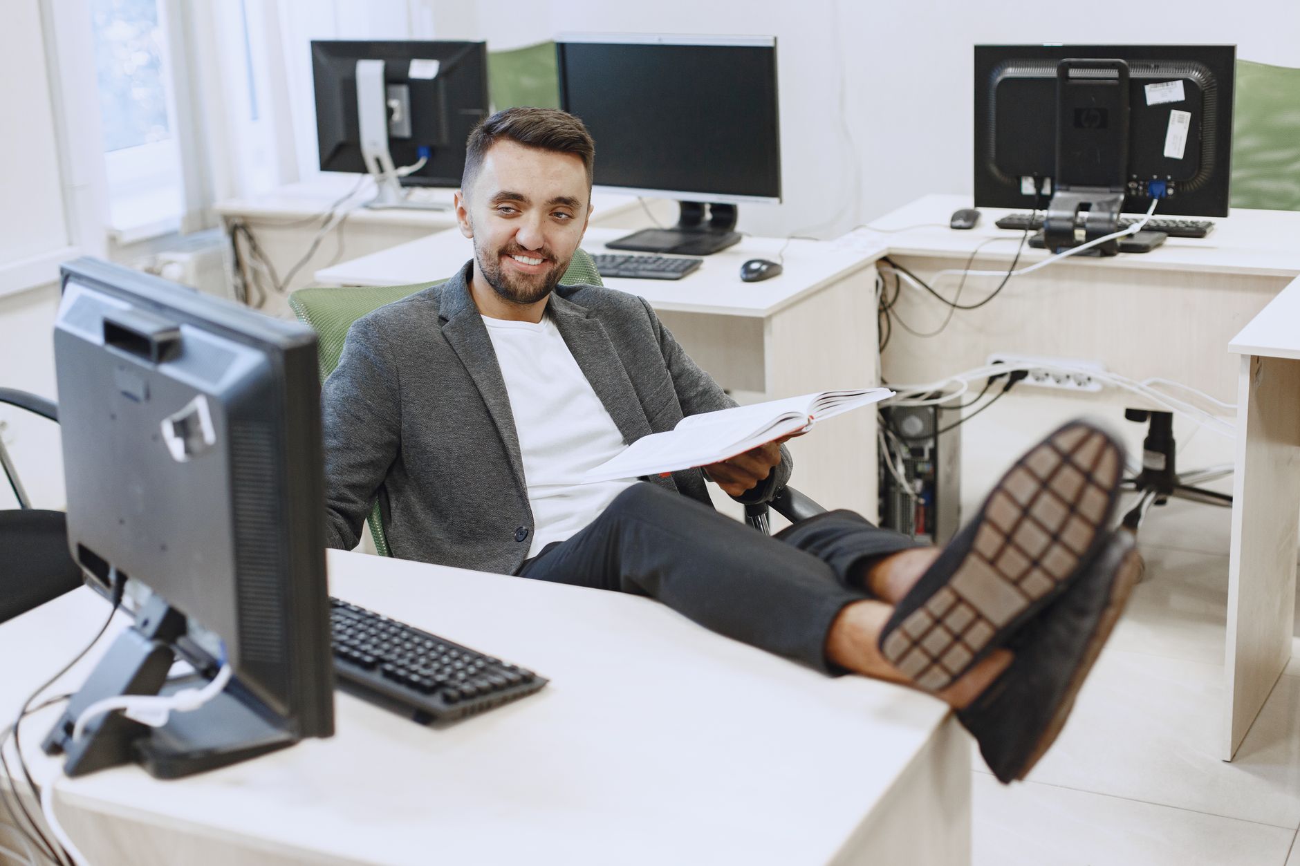 Businessman in casual office setting, relaxing at his desk with computers.