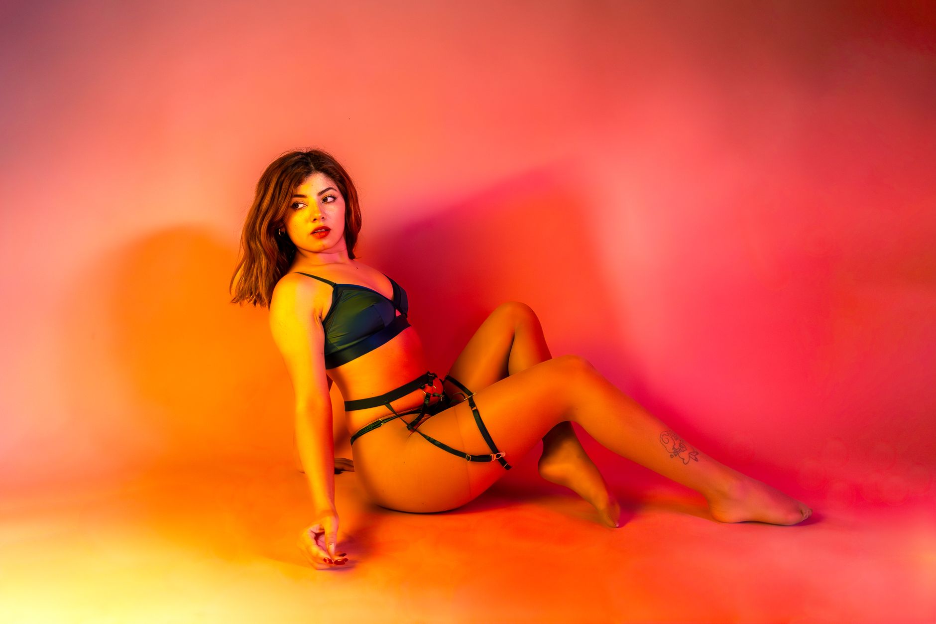 Sensual studio shoot of a woman in lingerie with vibrant colors.