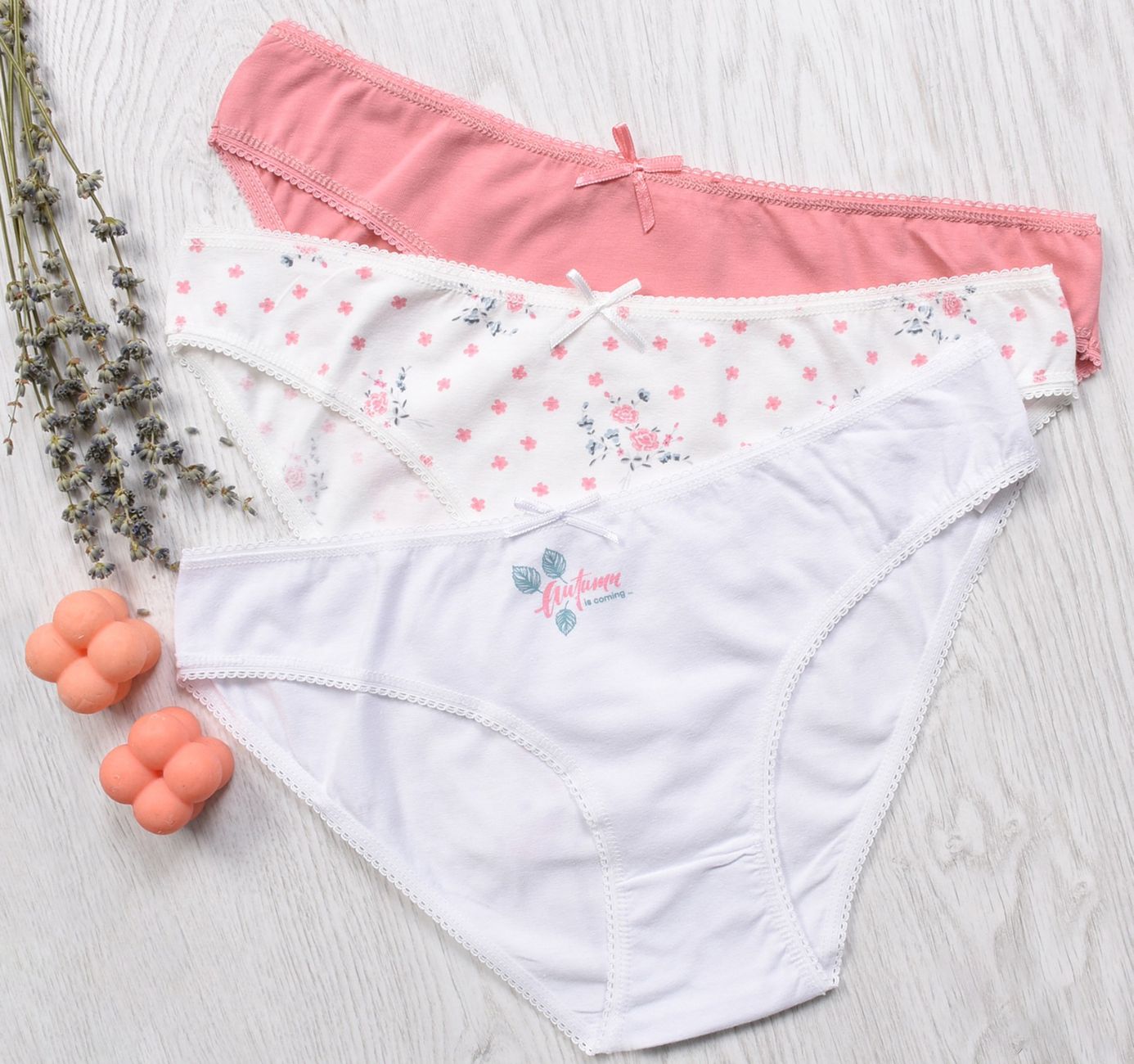 Three pairs of women's panties in pastel colors and lavender on wooden background.