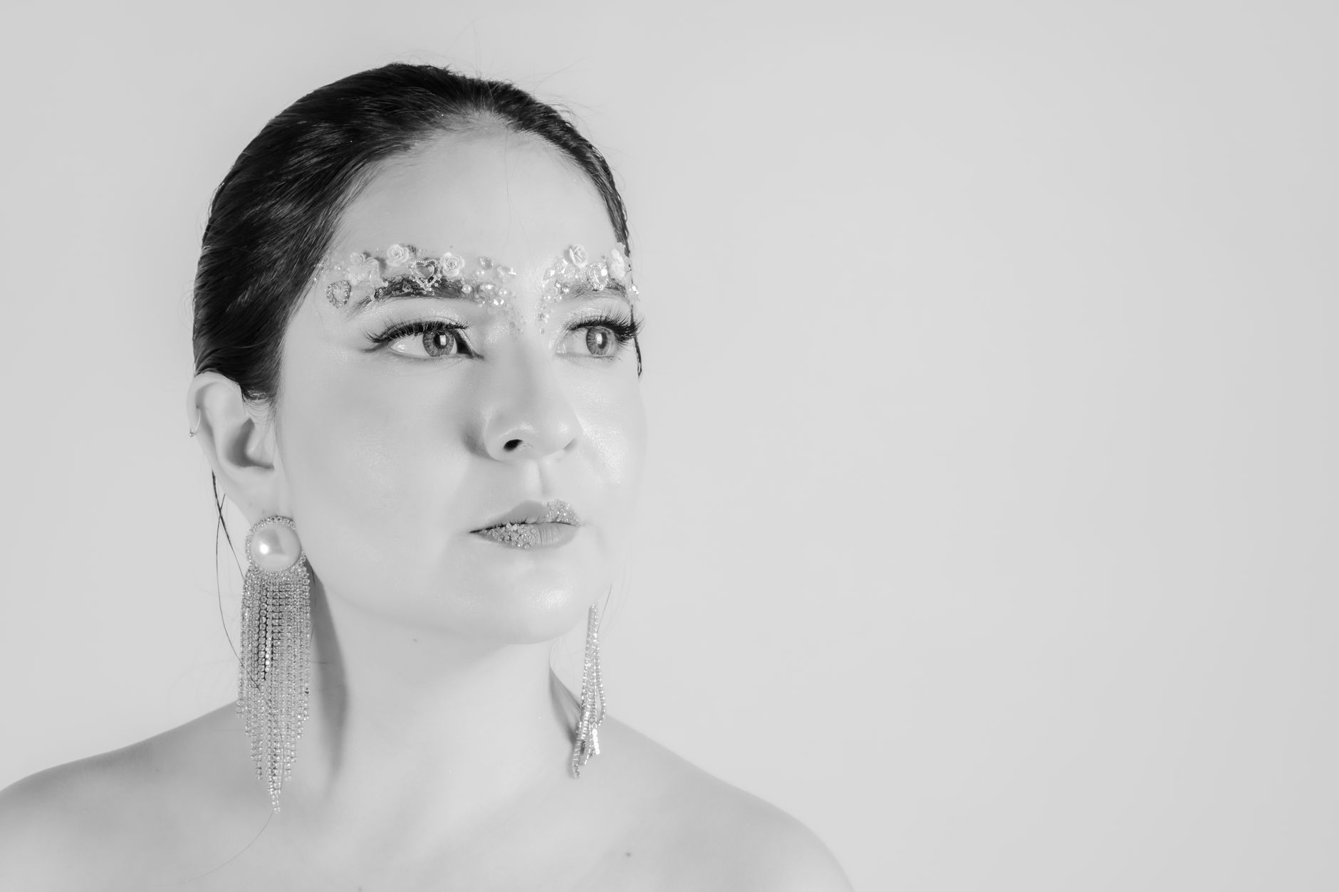 Striking black and white portrait of a woman with creative makeup and stylish earrings.