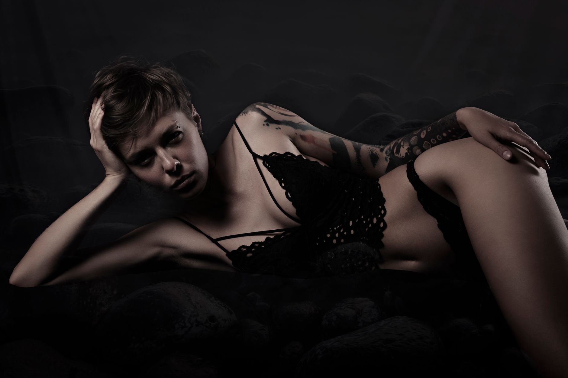 A dramatic, artistic portrait of a tattooed woman in lingerie, conveying mood and style.