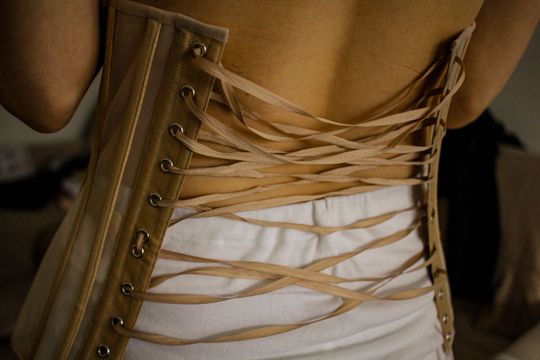 Close-up of a woman wearing a laced corset from the back, showcasing sensuality and elegance.