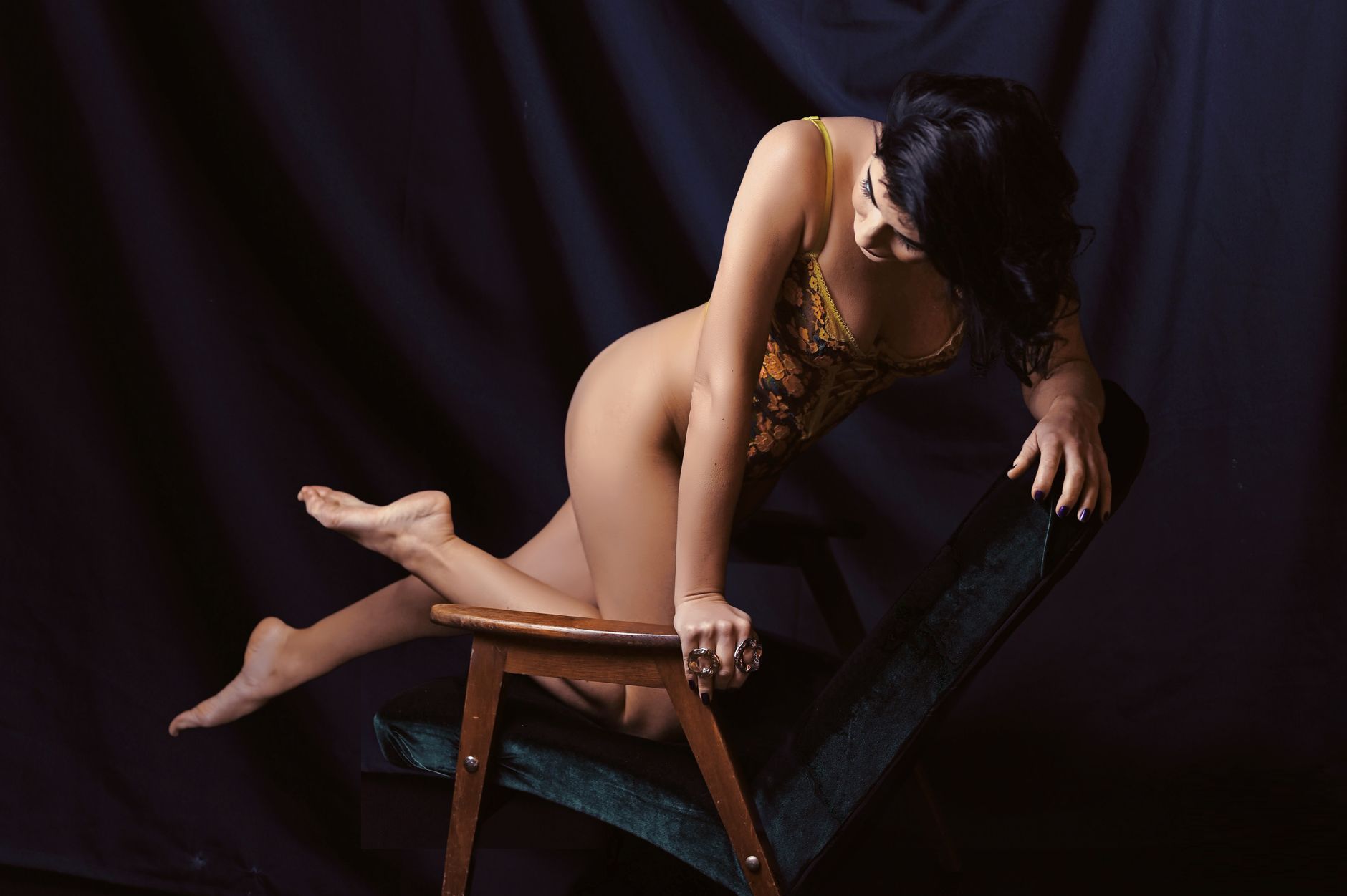 Elegant portrait of a woman posing in lingerie against a dark backdrop, exuding confidence.