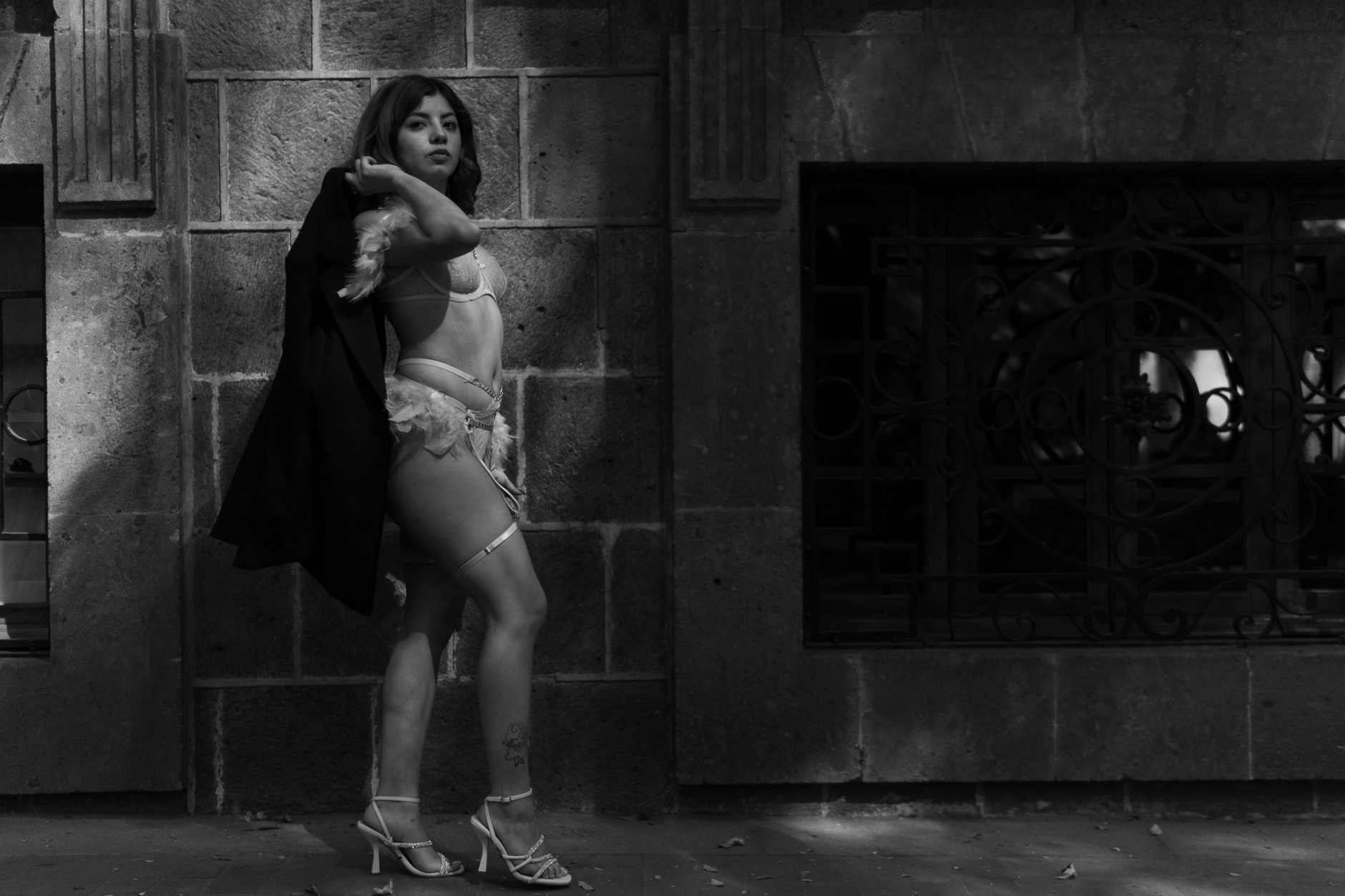 Elegant black and white portrait of a woman in lingerie posing against a brick wall in Mexico City.