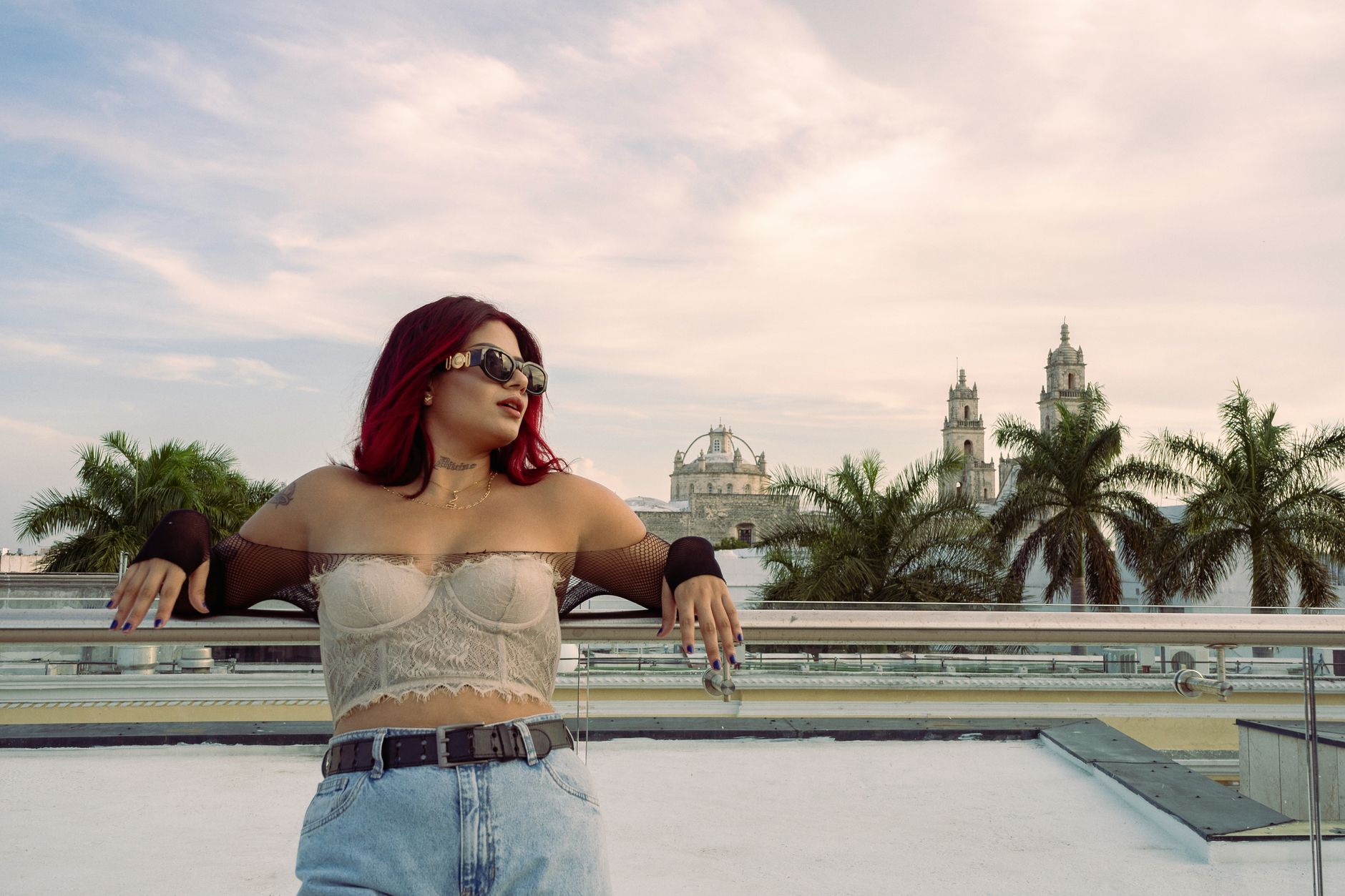 Stylish woman posing on a terrace in Mérida, showcasing trendy fashion with cathedral backdrop.
