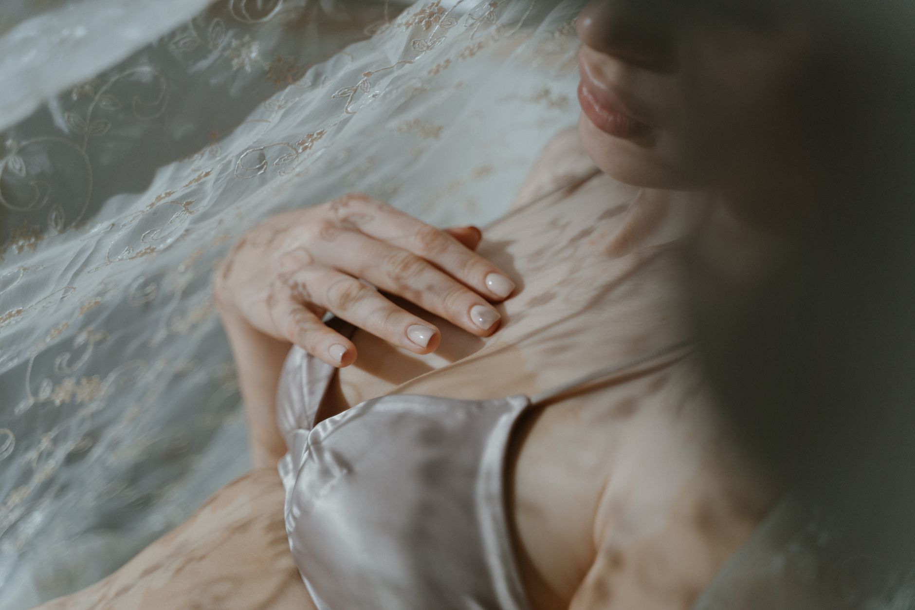 A gentle close-up of a woman in lingerie under sheer fabric, evoking elegance and sensuality.