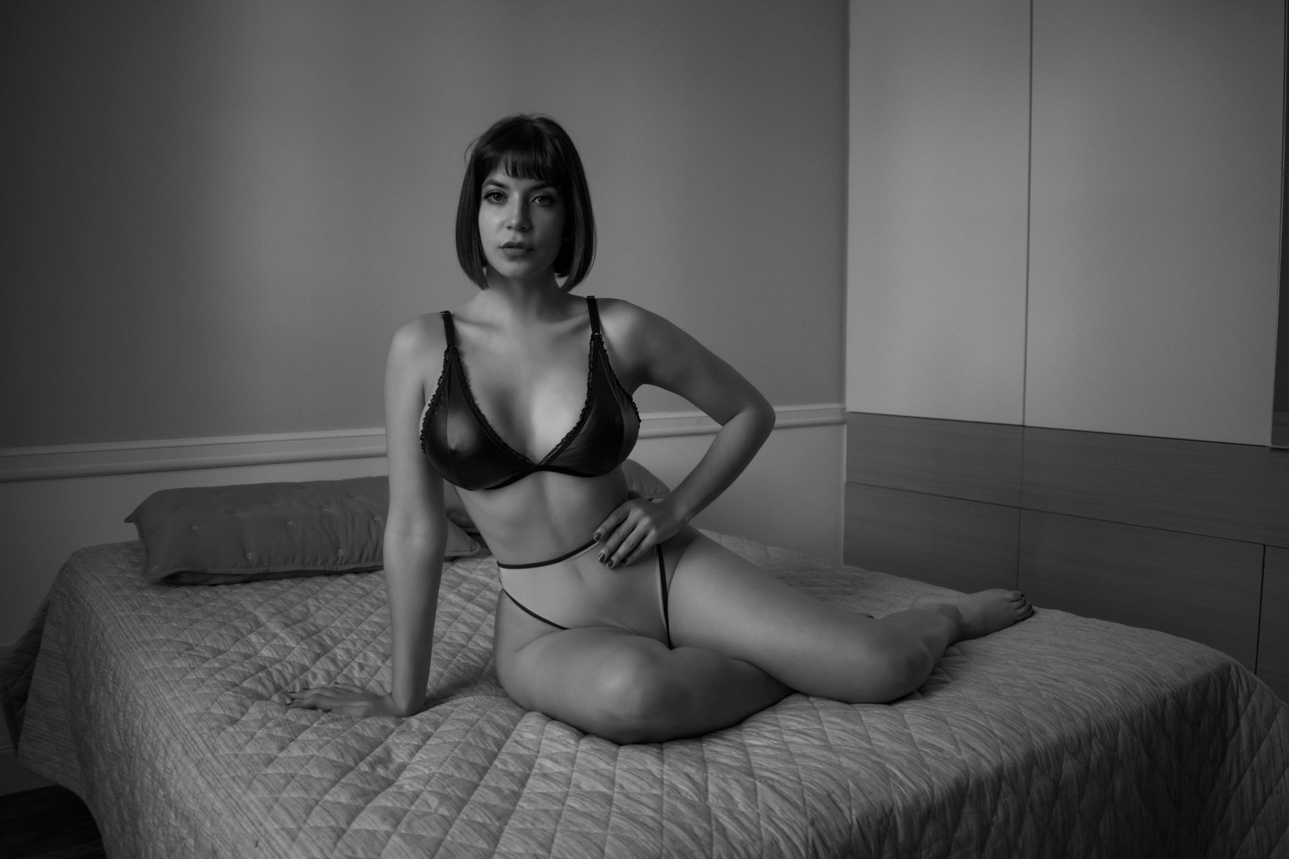 Black and white portrait of a woman in lingerie sitting on a bed in Buenos Aires.