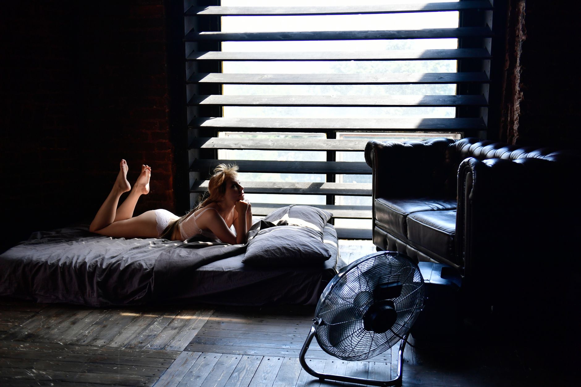 Woman in lingerie relaxing on bed by a window, creating a chic and modern vibe.