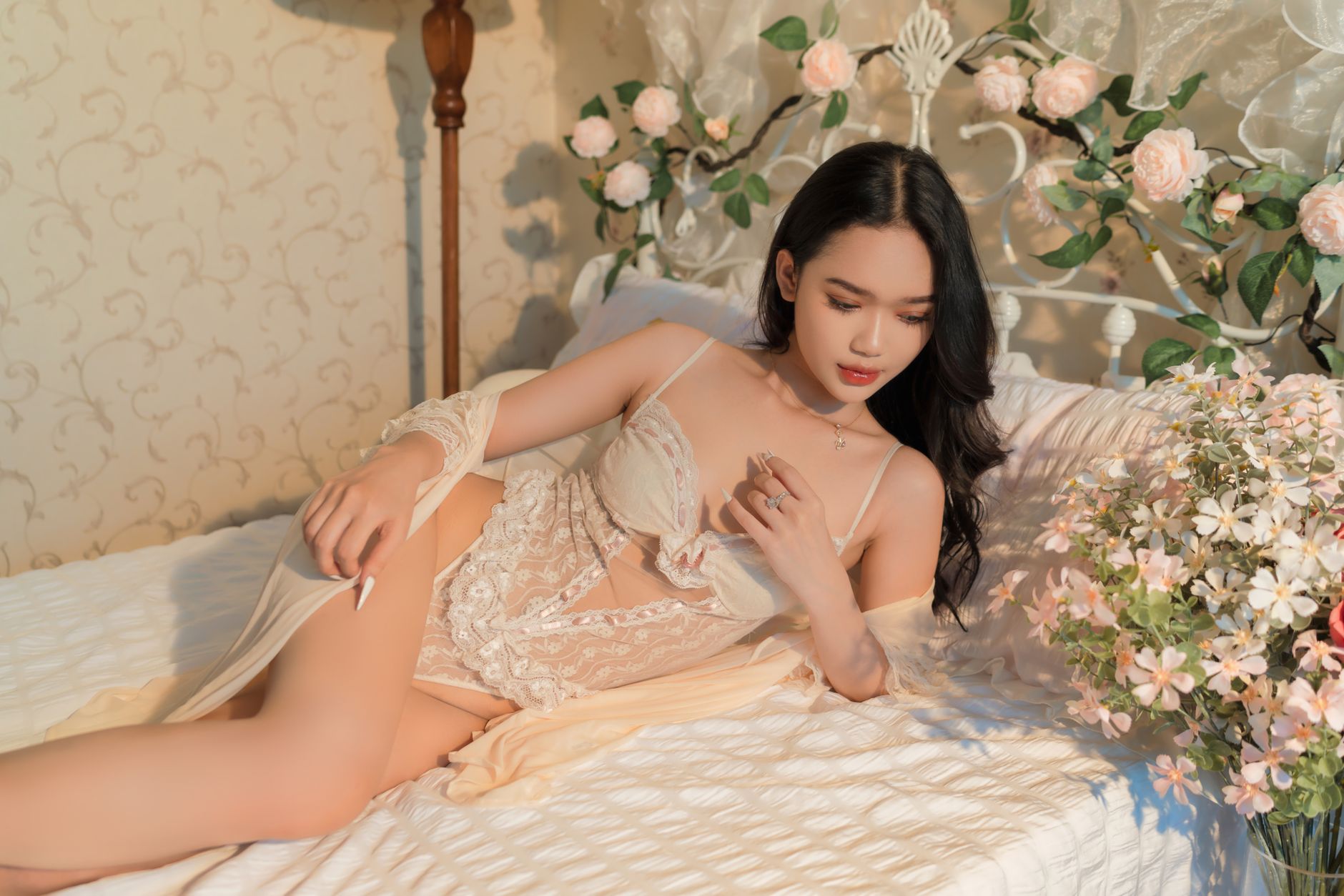 A woman in lace lingerie relaxing in a floral-decorated bedroom, exuding elegance.