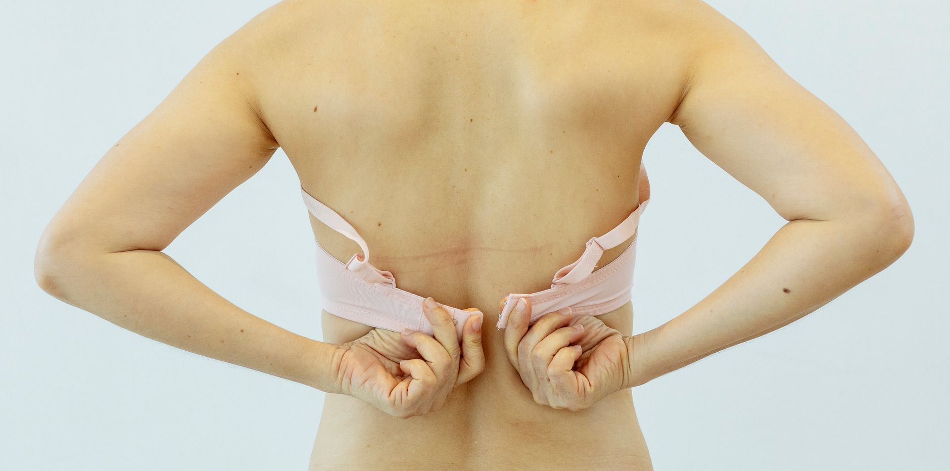 Back view of crop anonymous female with bra on white background of studio