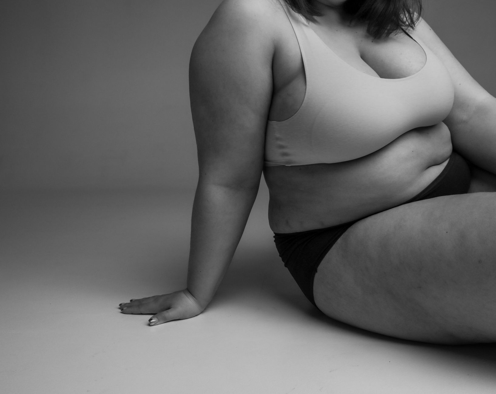 Elegant black and white portrait of a plus-size model in a studio setting, embracing body positivity.