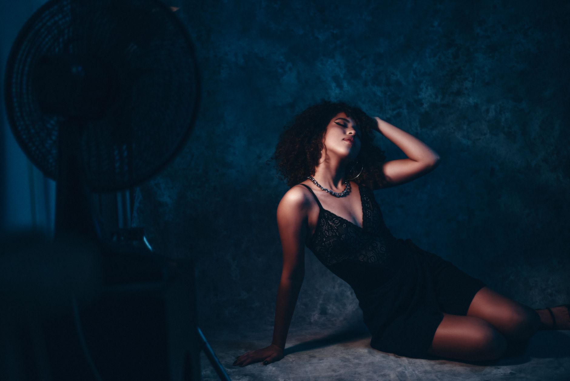 Stylish African American woman posing in a sleek black dress in a studio environment.