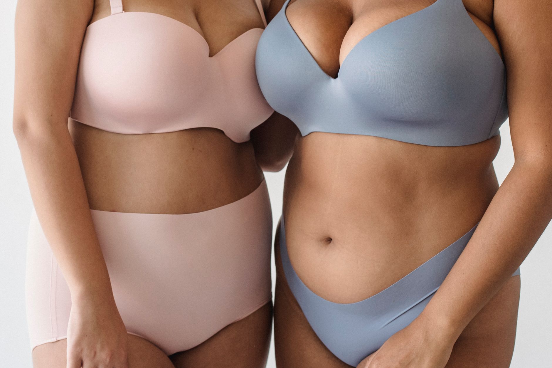 Two women standing close-up, showcasing body positivity in lingerie.
