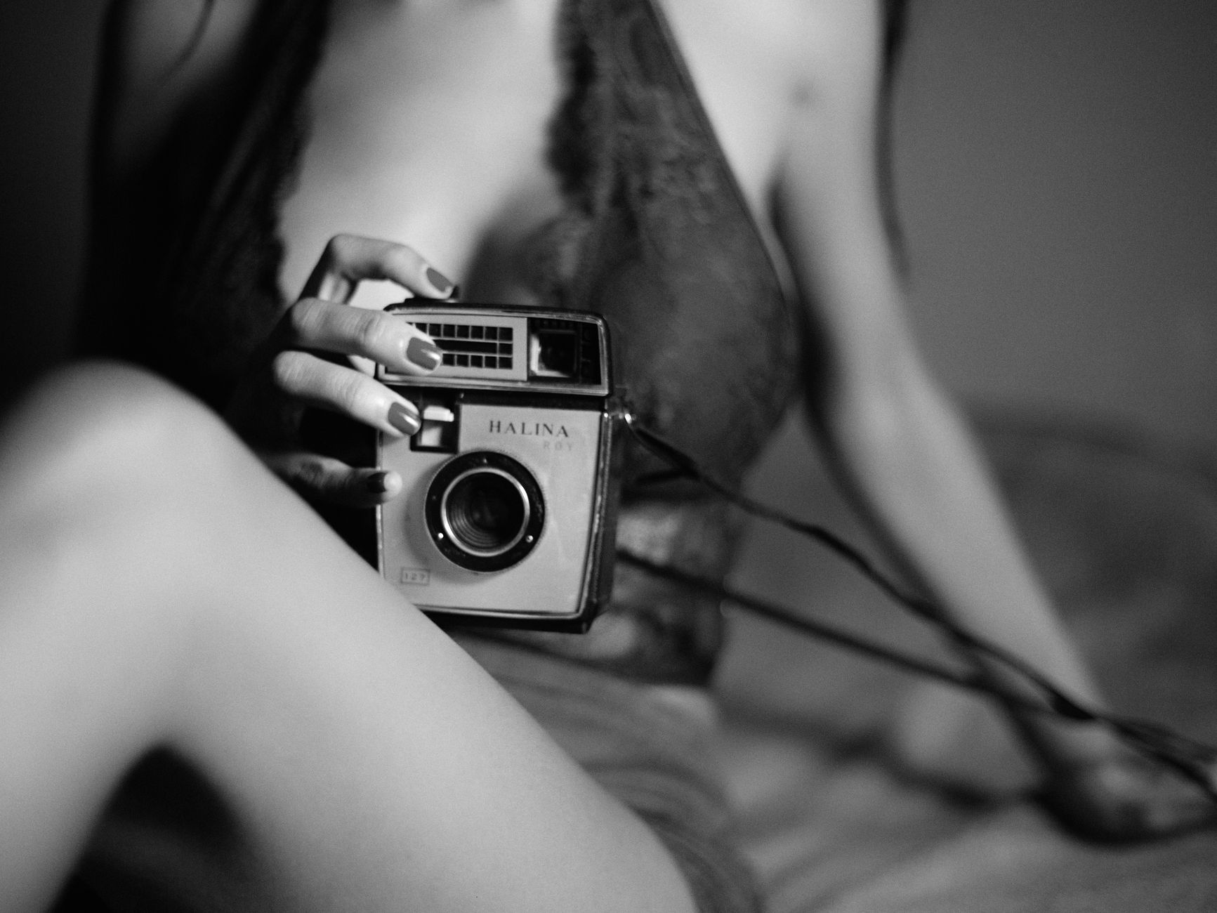 Artistic black and white photo featuring a woman holding a vintage Halina camera.