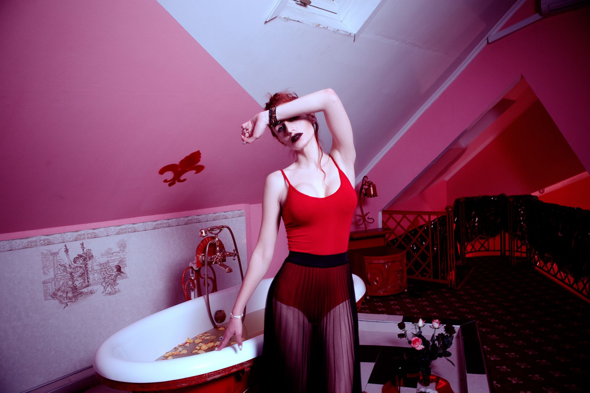 Stylish woman in red attire posing in a uniquely decorated attic bathroom.