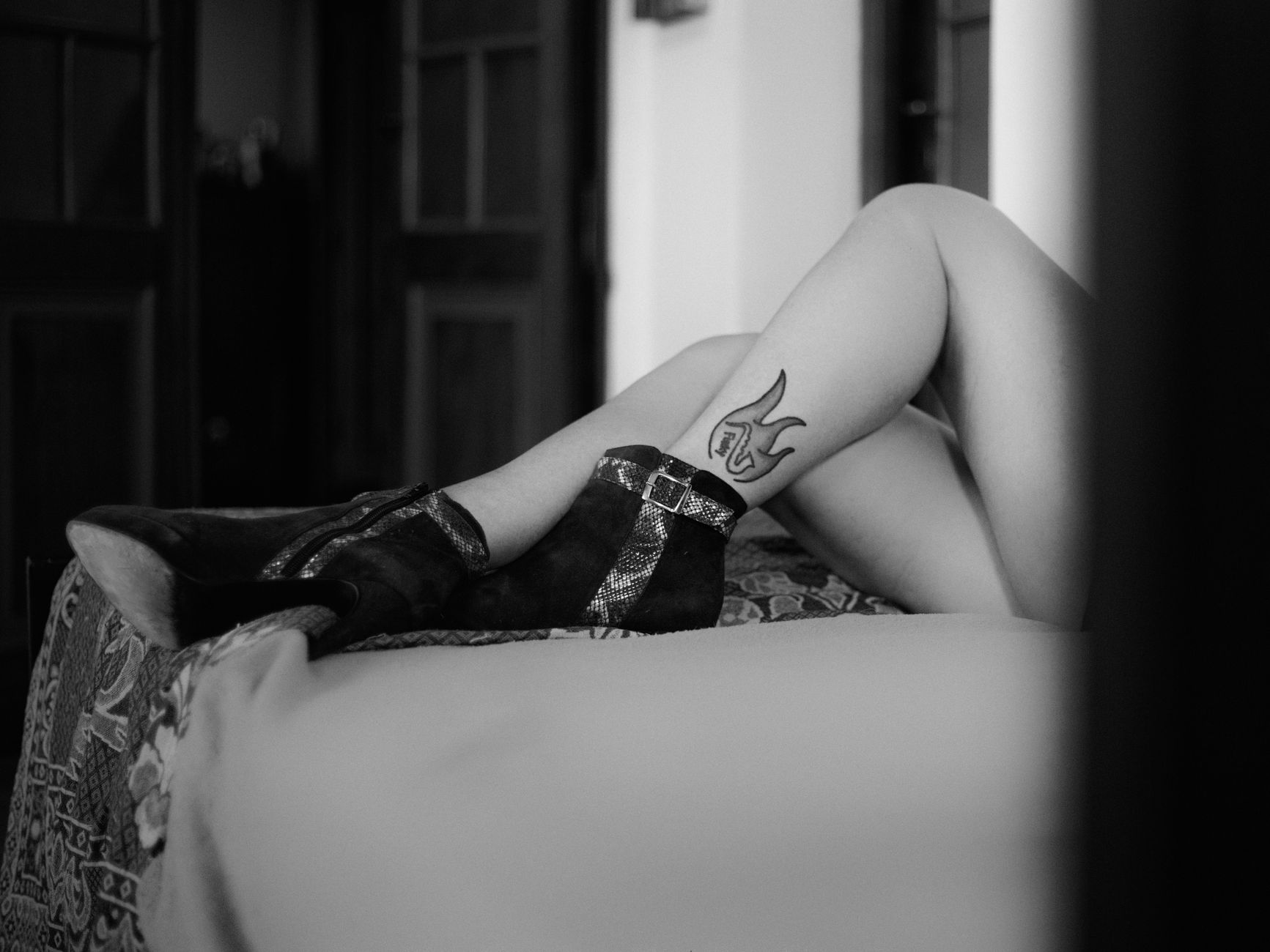 Artistic black and white photo of tattooed legs with boots, creating a moody atmosphere.