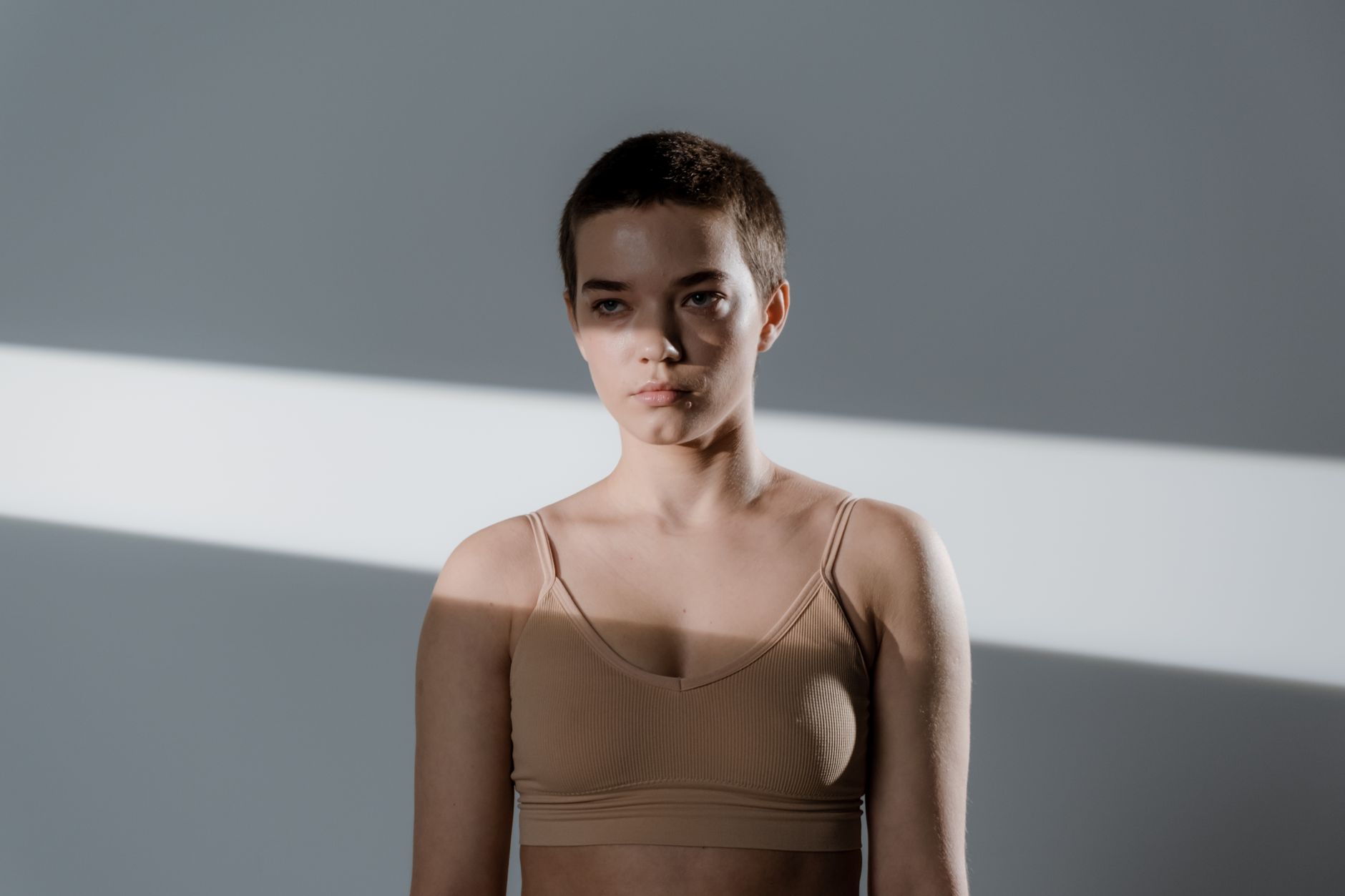 Portrait of a young woman with short hair in soft studio lighting.