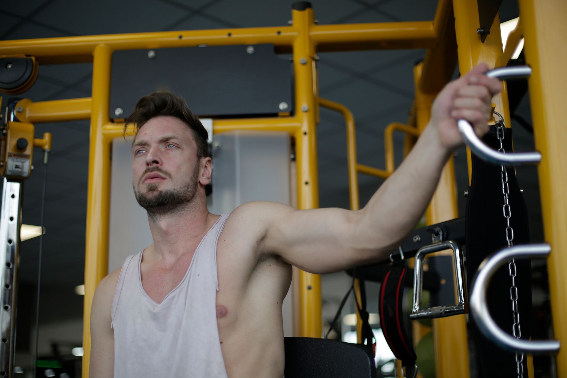 Focused man working out on gym equipment, showcasing strength and fitness.