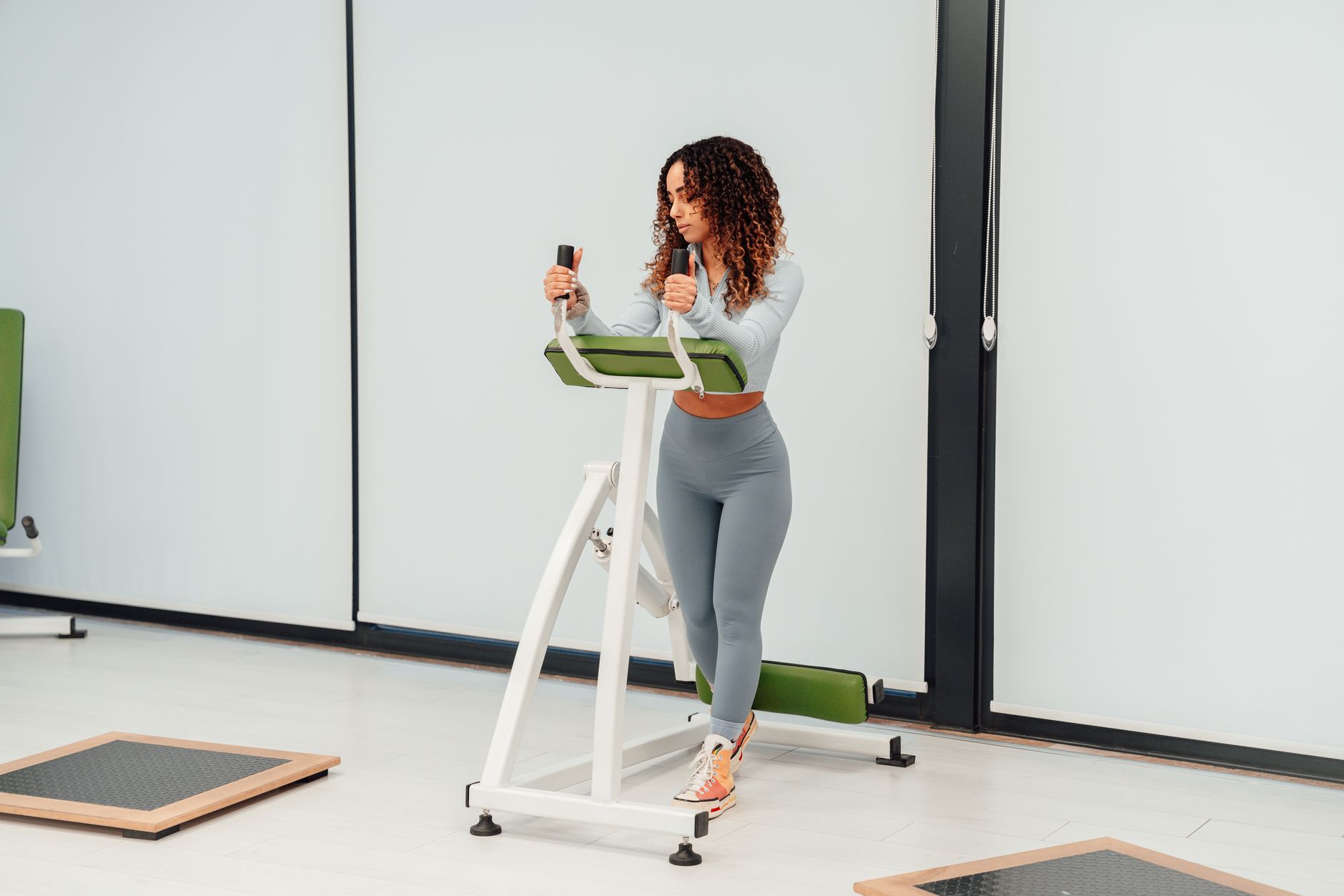 A young woman exercises on fitness equipment in a modern indoor gym setting, embracing a healthy lifestyle.