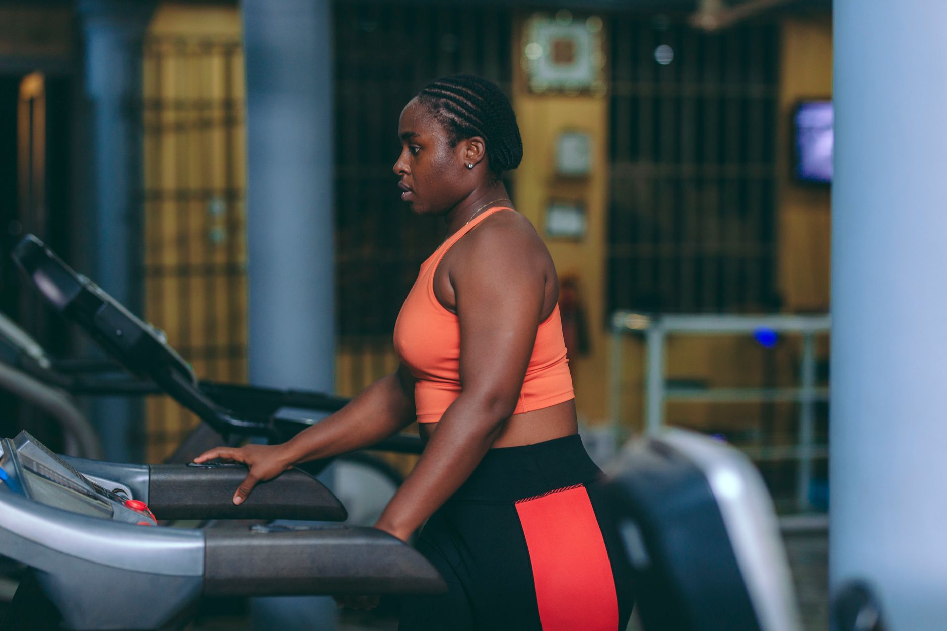 African woman working out on treadmill in an indoor gym setting.