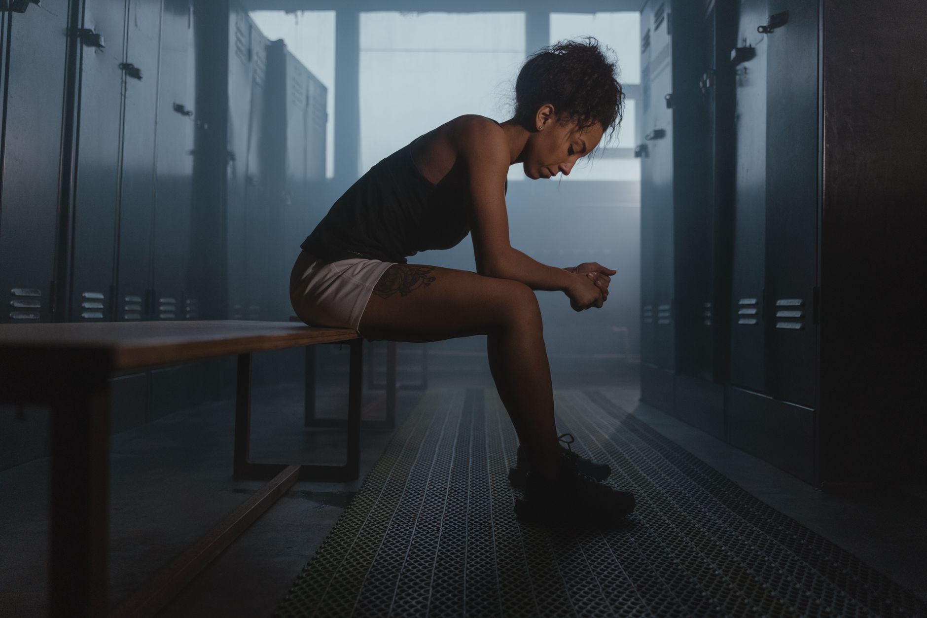 A contemplative athlete sits in a dimly lit locker room, embodying strength and introspection.
