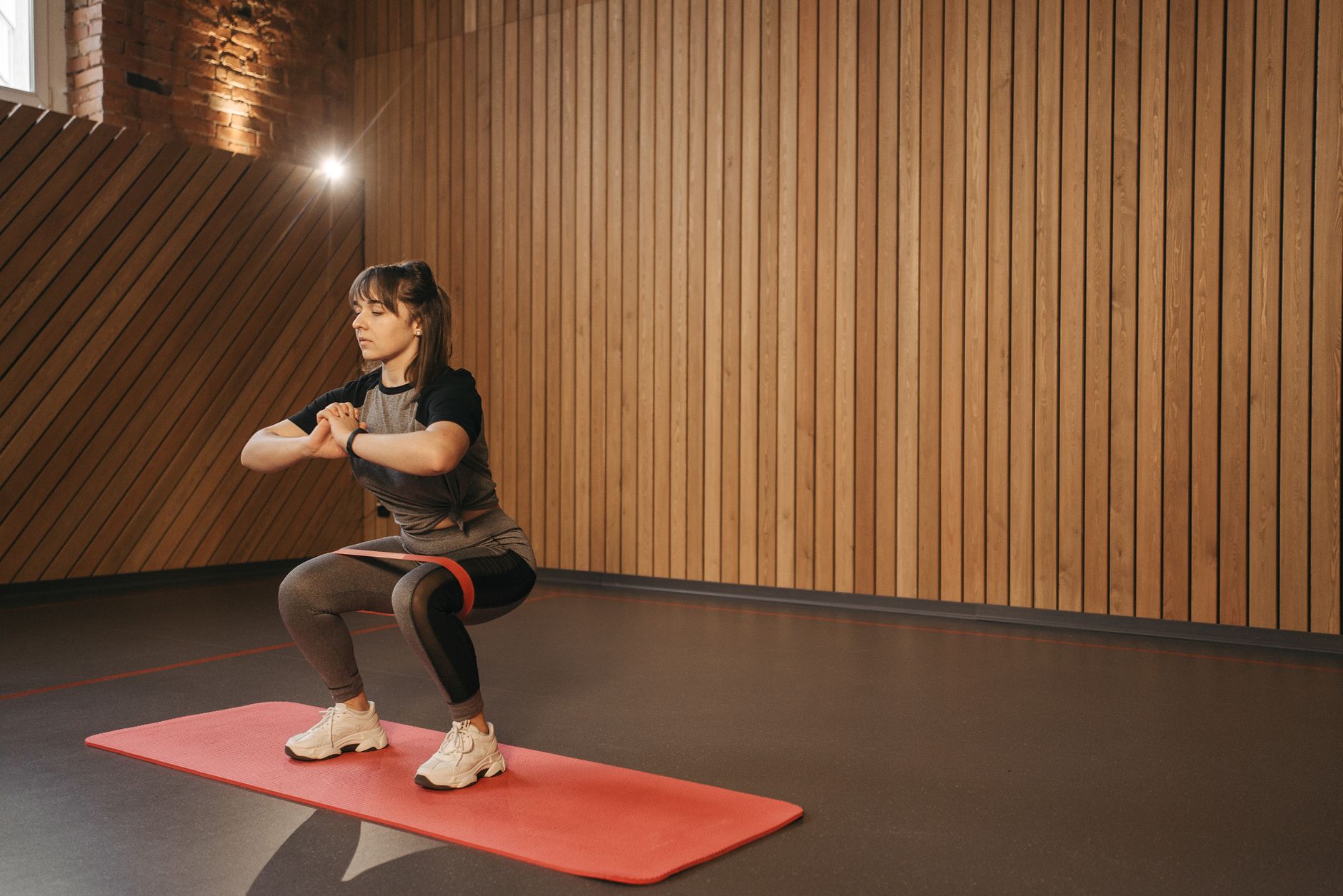 Young woman exercises indoors with resistance band on mat for fitness