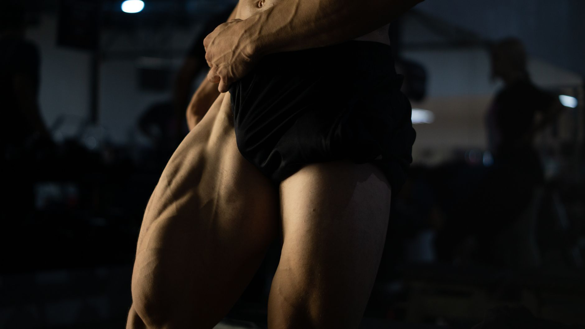 Dynamic close-up of a man's muscular thighs in a gym environment, highlighting strength.