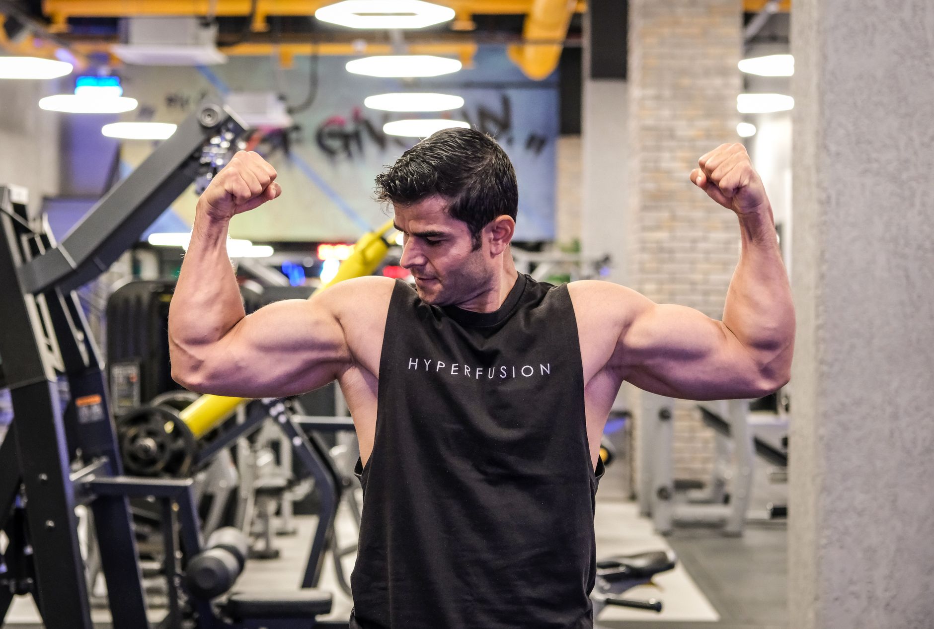 A muscular man flexes his biceps in a modern İstanbul gym, showcasing strength and fitness.