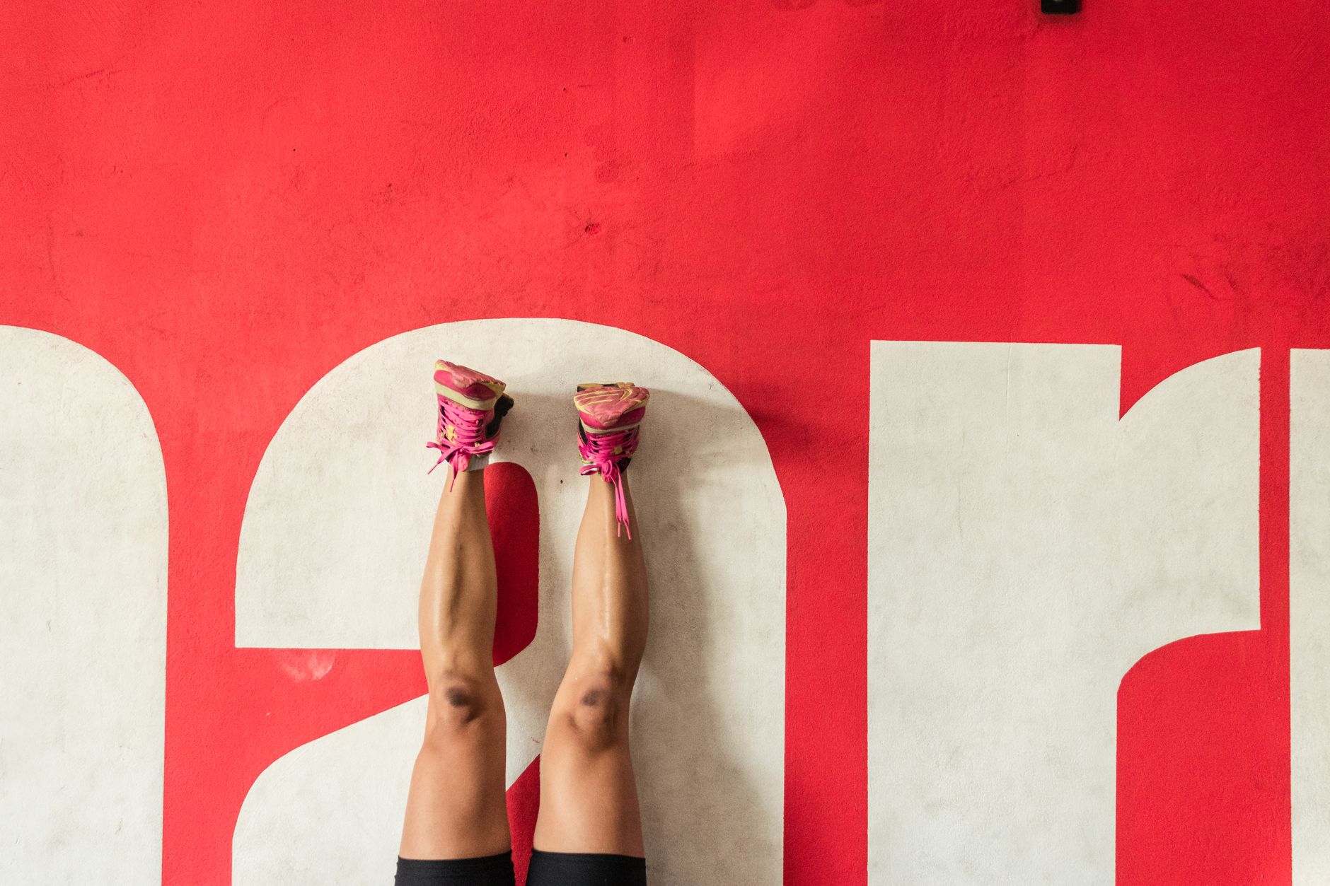 Creative photo showing a person's legs up against a bold red wall with text.