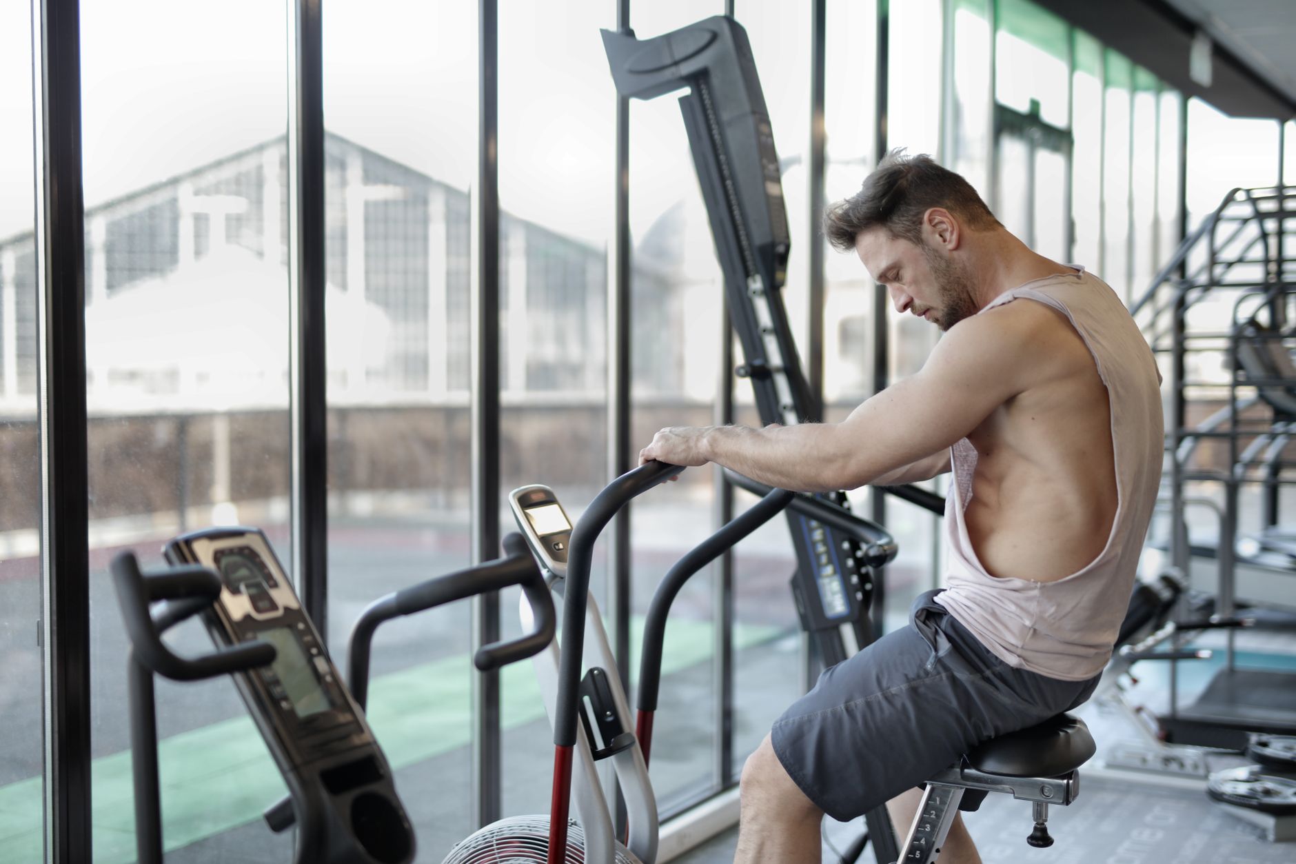 Side view of muscular male in sportswear training on exercise bike in modern fitness center
