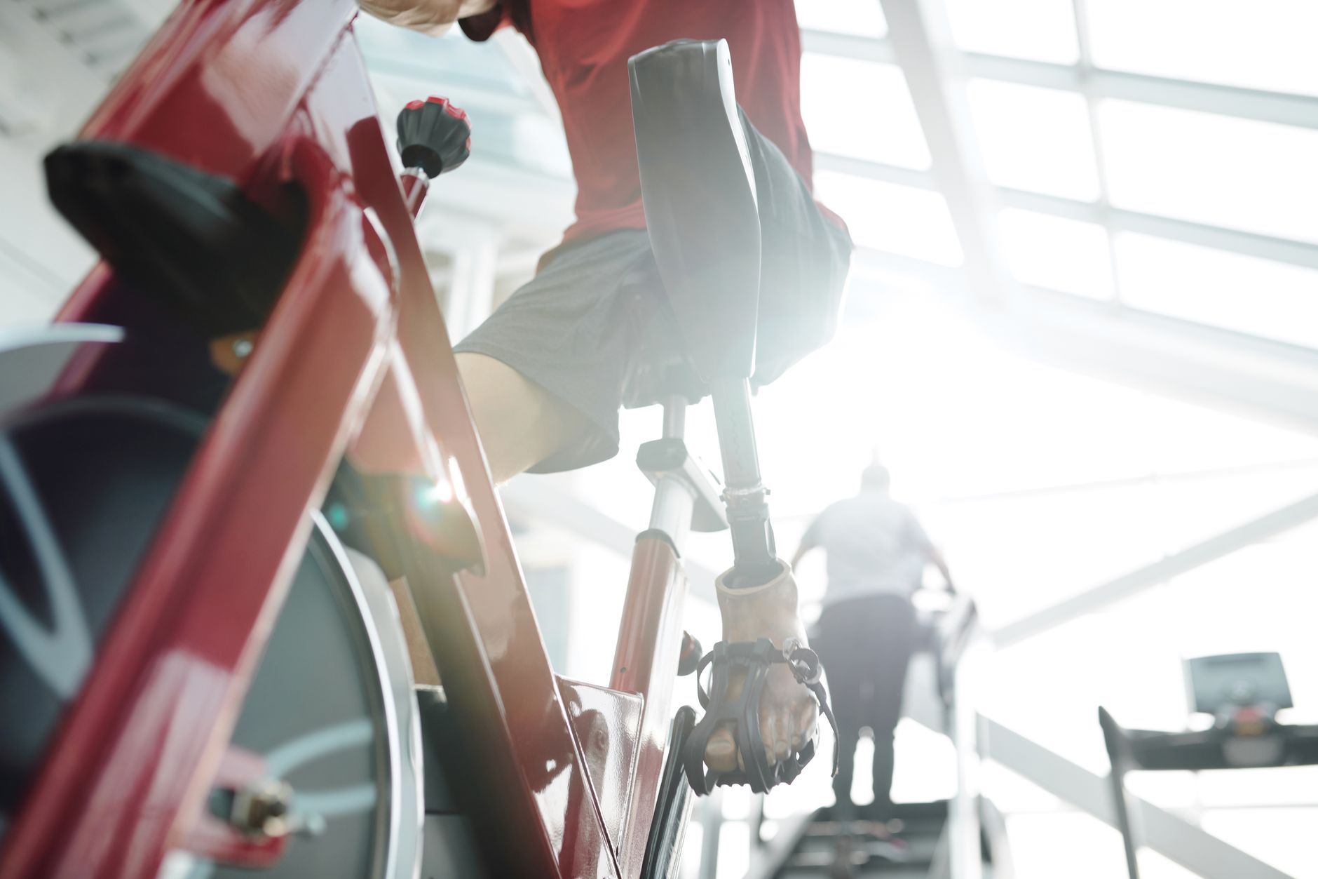 Motivated athlete with prosthetic leg working out on a stationary bike, demonstrating strength and resilience.