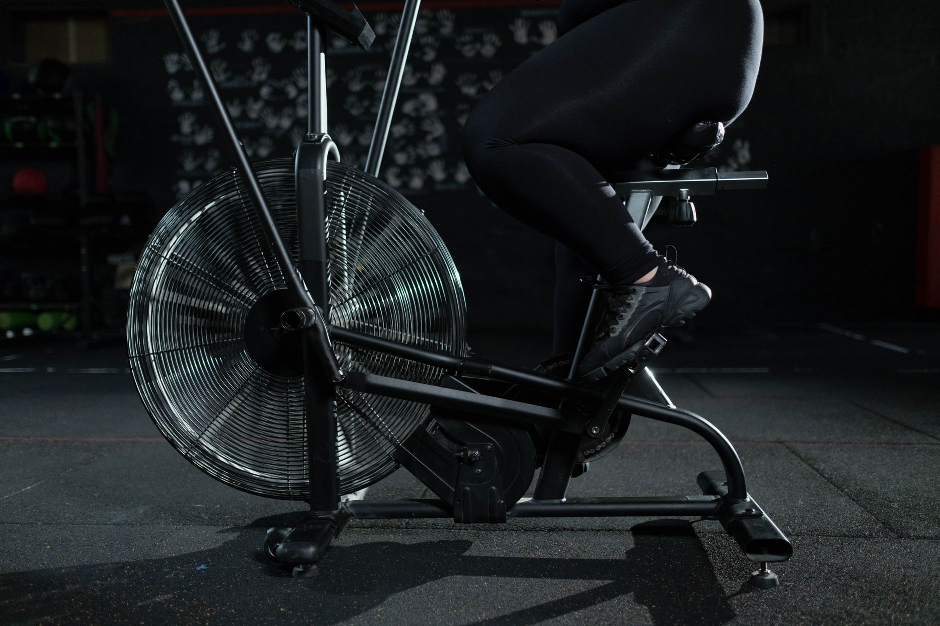 Close-up of a woman exercising on a stationary bike in a dimly lit gym.