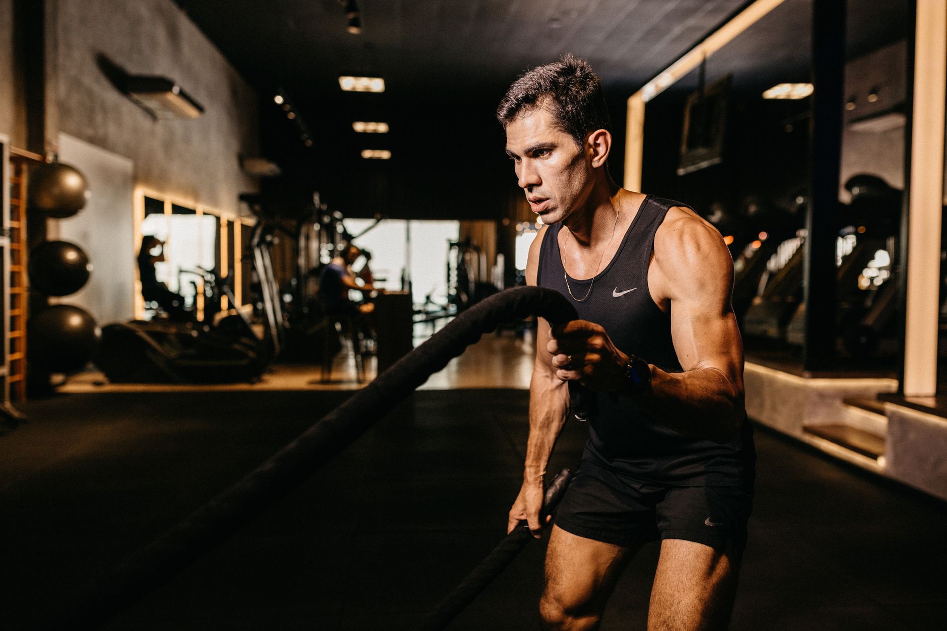 Man exercising with battle ropes in a gym, showcasing strength and determination.