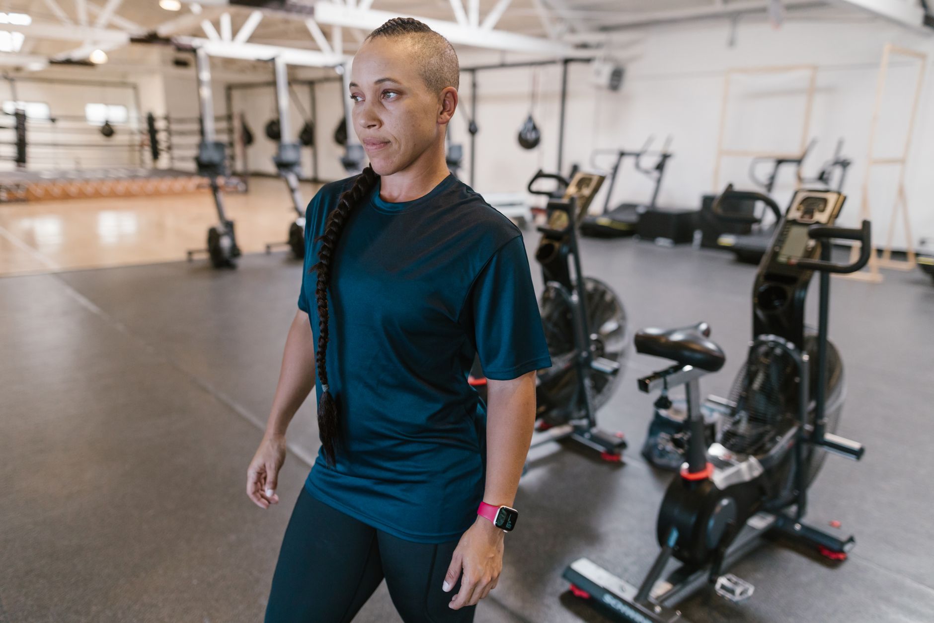 Focused woman in gym preparing for her workout surrounded by exercise equipment.