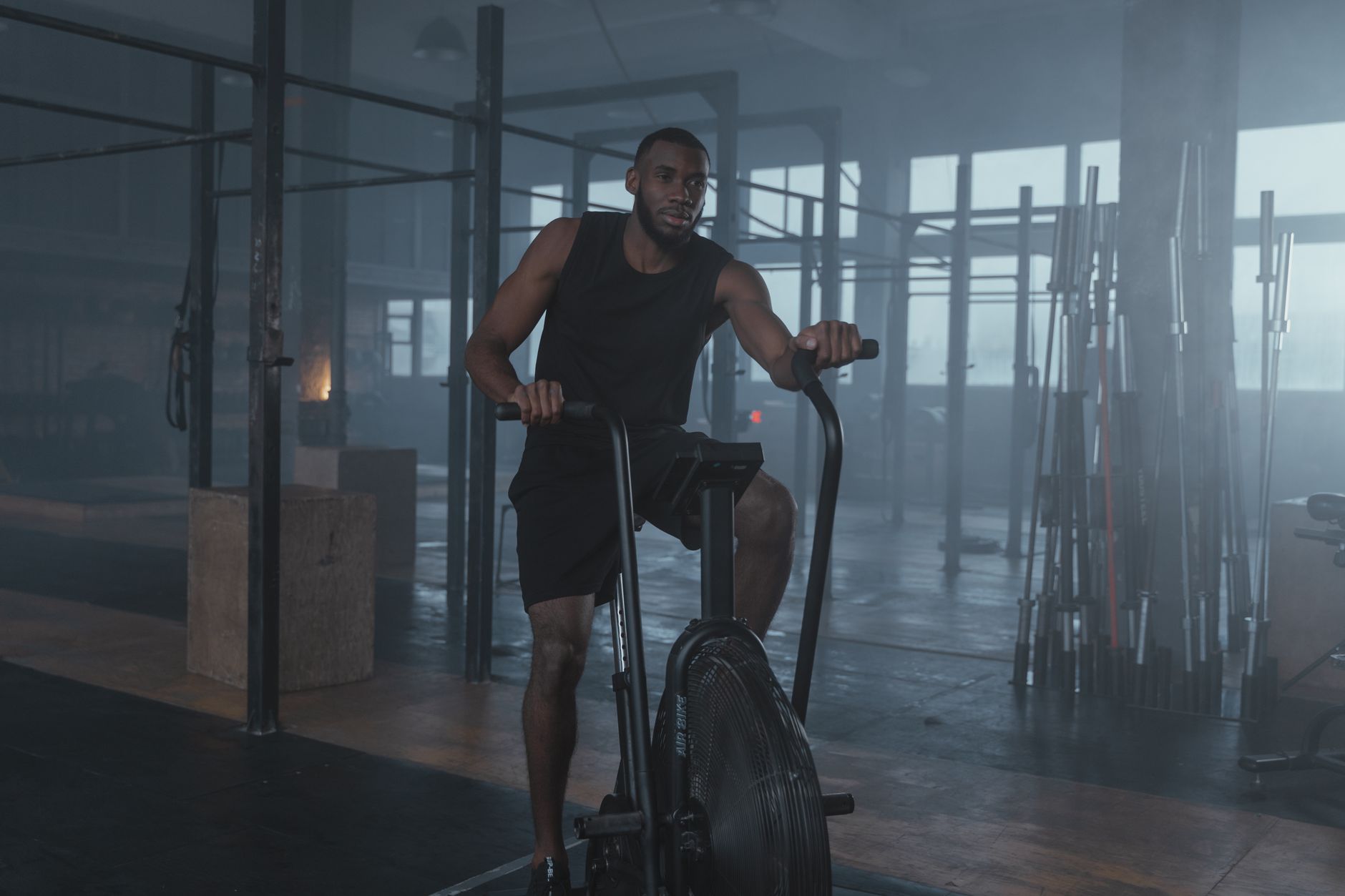 Focused man in gym working out on elliptical machine, promoting fitness and lifestyle.