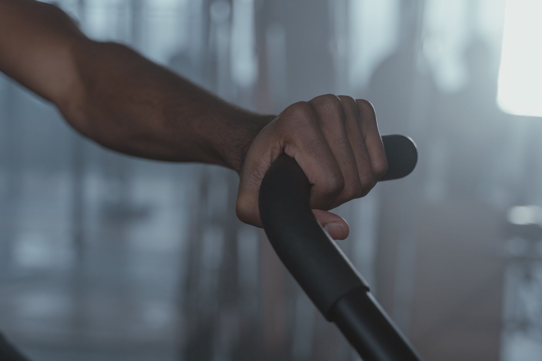 Focused shot of a person's hand firmly gripping gym equipment indoors.