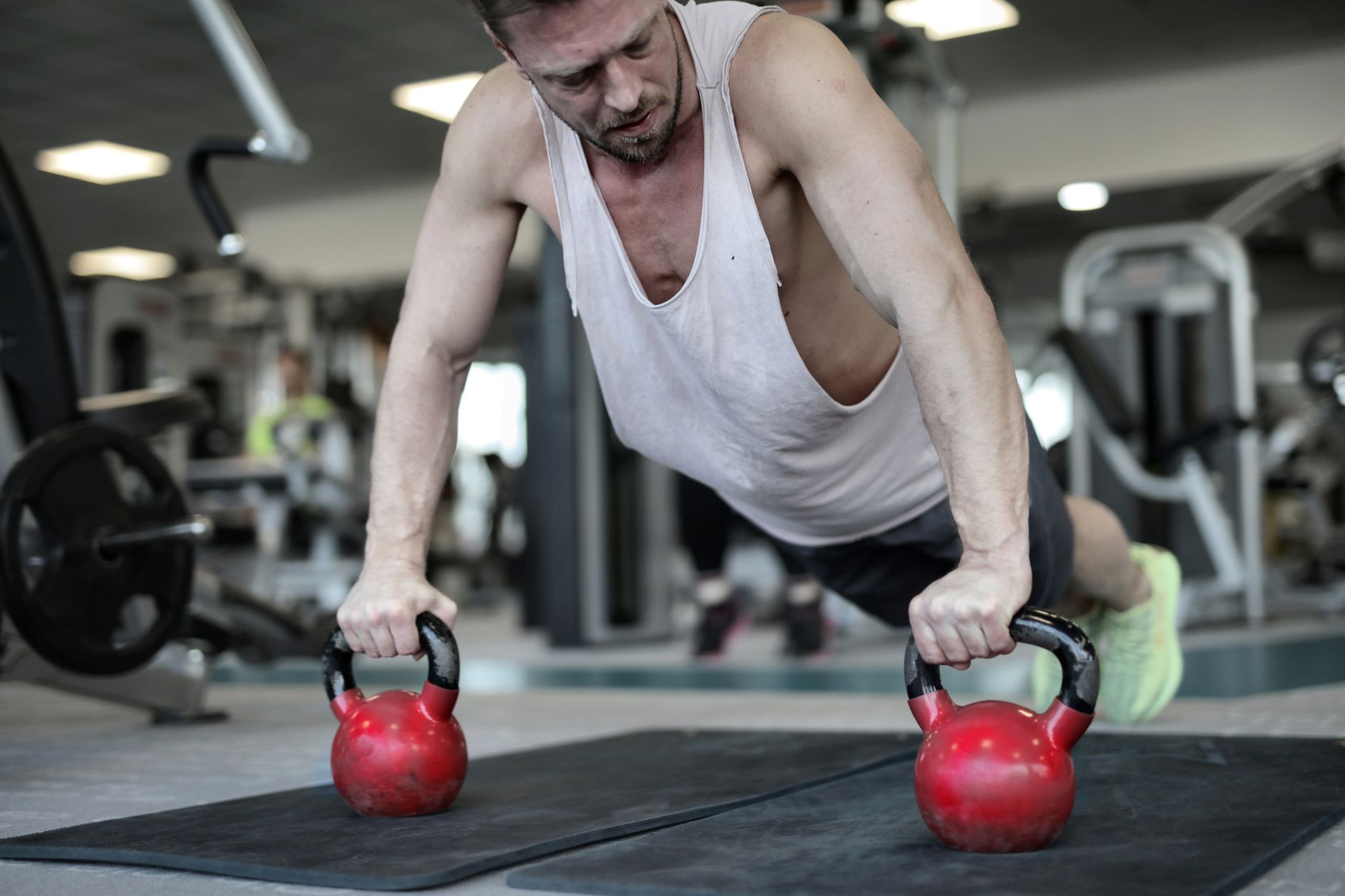 Low angle of fit male athlete in sportswear doing push ups on metal equipment in modern gym while making effort during intense workout
