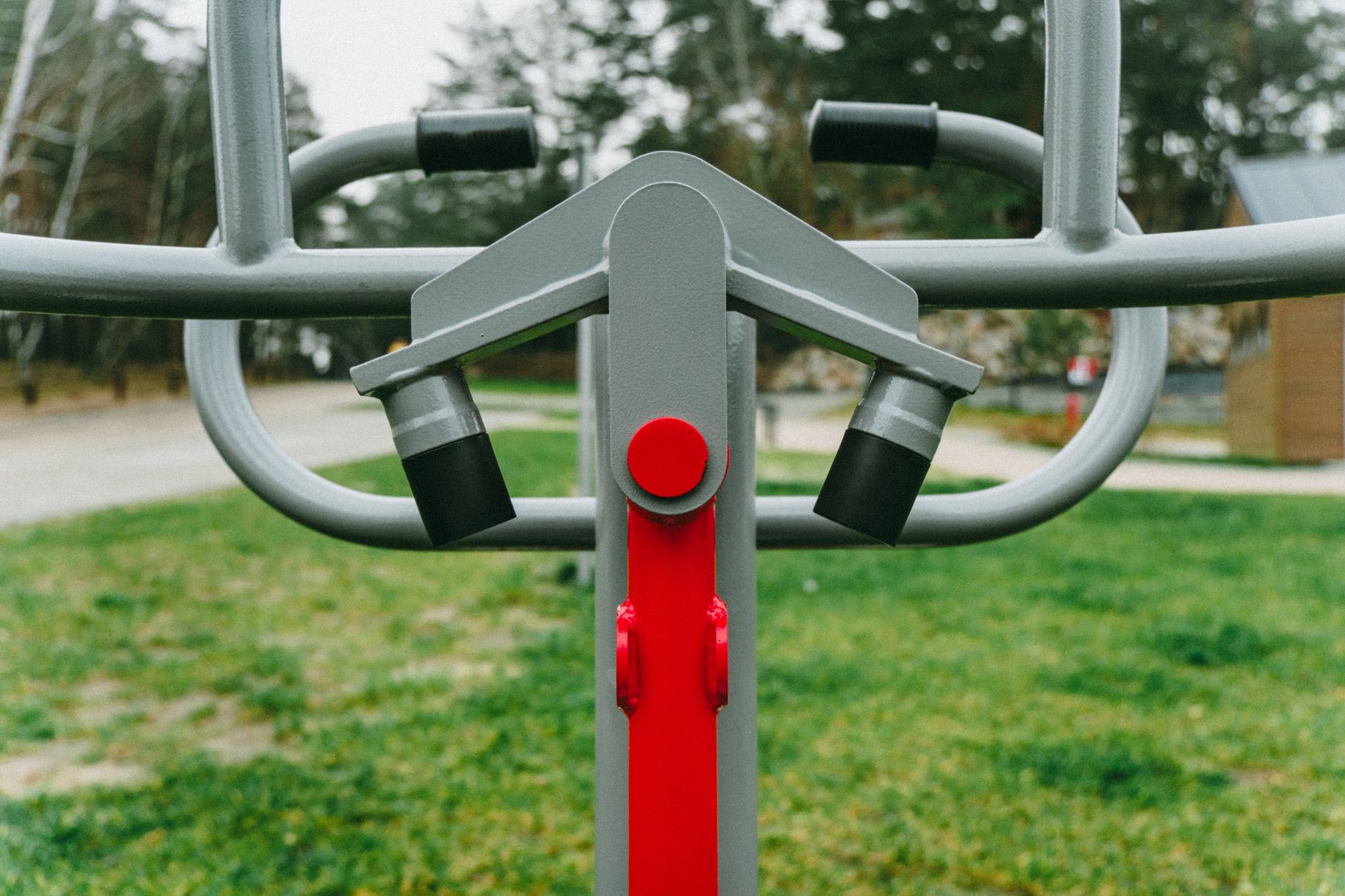 Outdoor exercise equipment with focus on red detail, set in a lush Polish park during spring.
