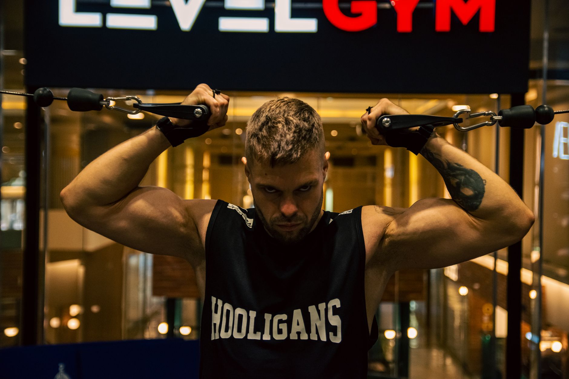 A muscular man exercises with gym equipment indoors, showcasing strength and determination.